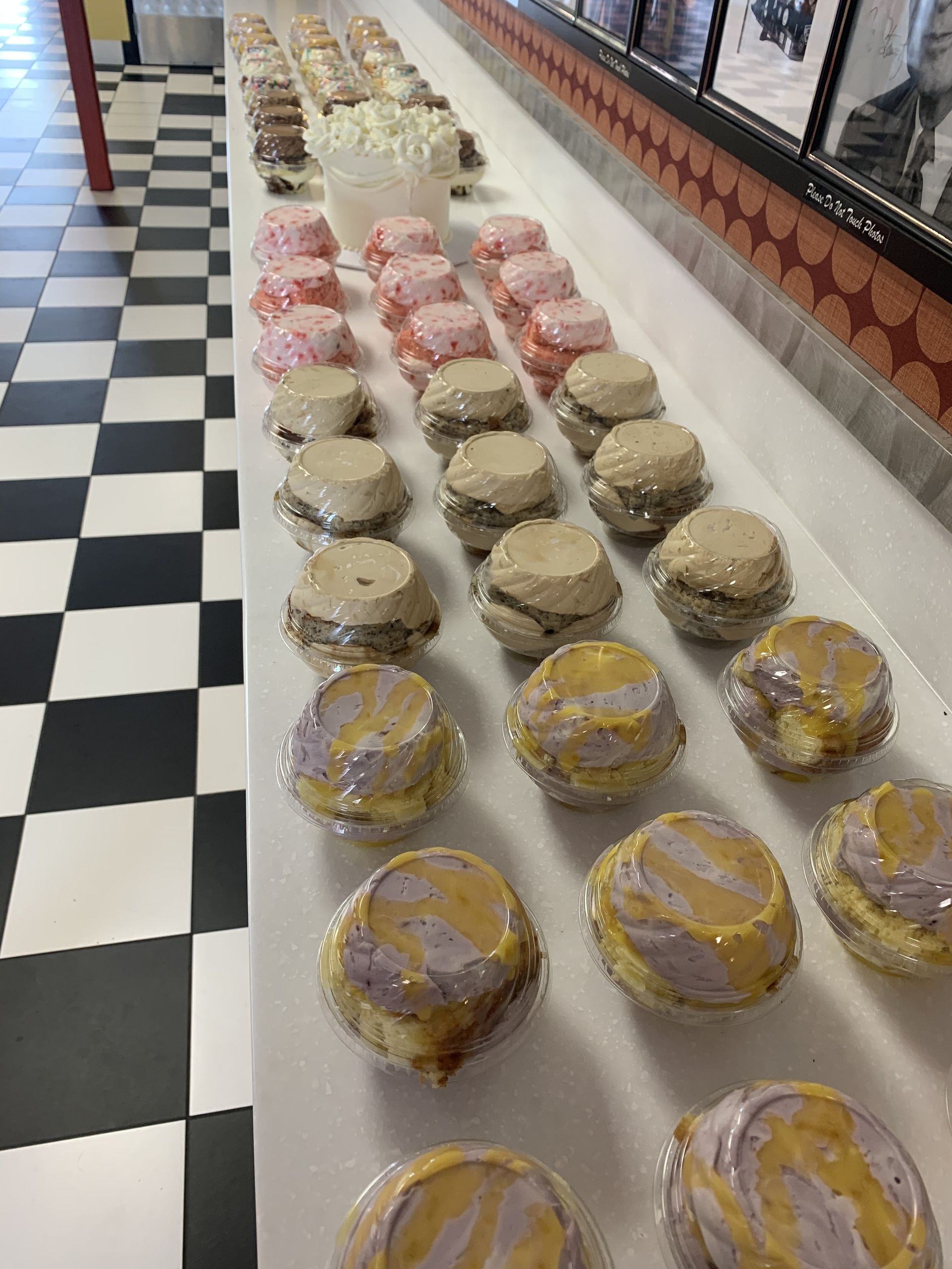 a bunch of cupcakes are lined up on a table in a bakery .
