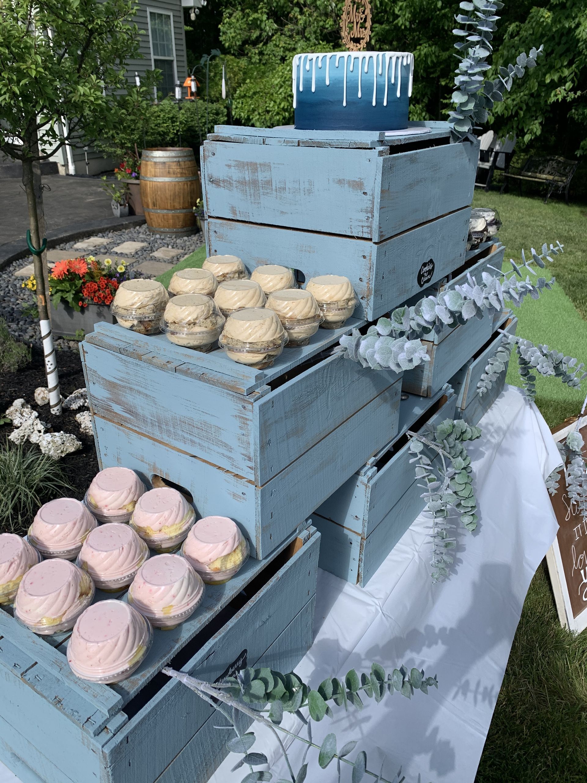 a table topped with blue wooden crates filled with cupcakes and a cake .