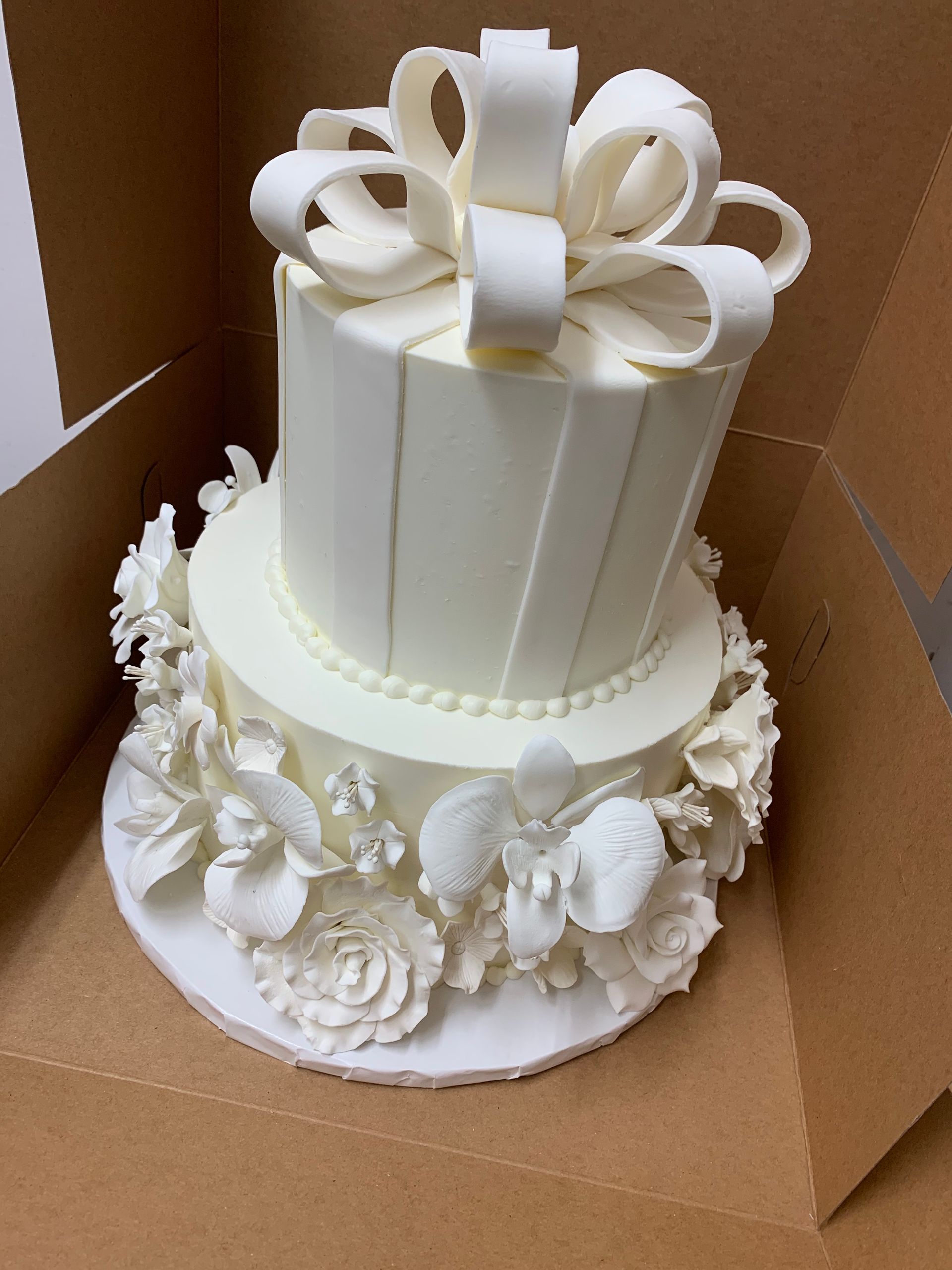 a white cake with a bow on top is in a box .