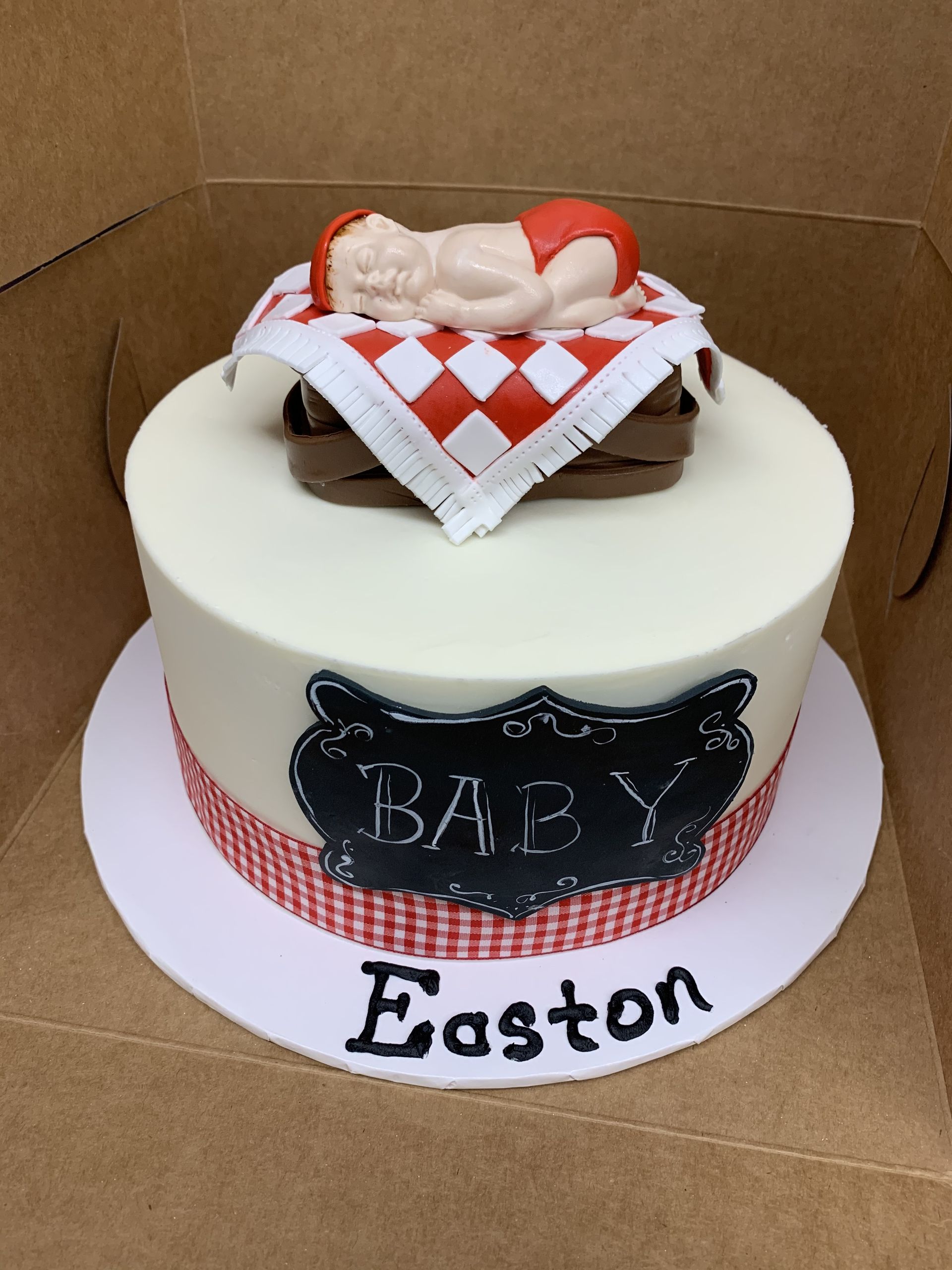 a baby shower cake for easton with a baby sleeping on a picnic blanket