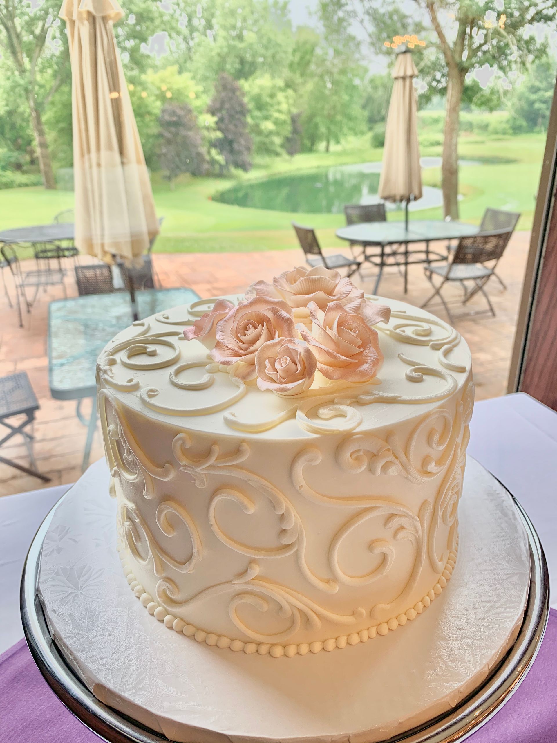 a white cake with pink roses on top is sitting on a table .