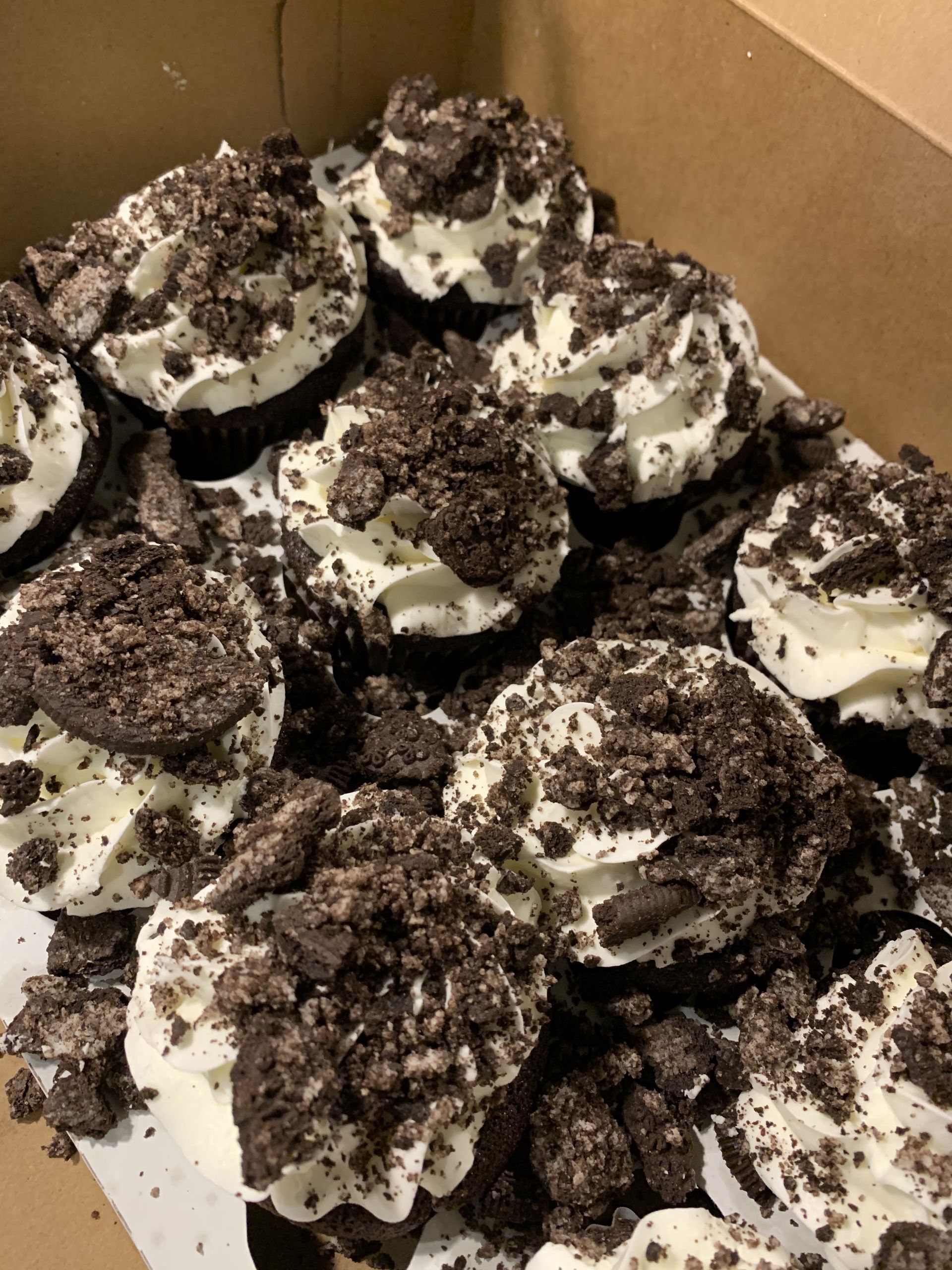 a box of oreo cupcakes with whipped cream and crumbs
