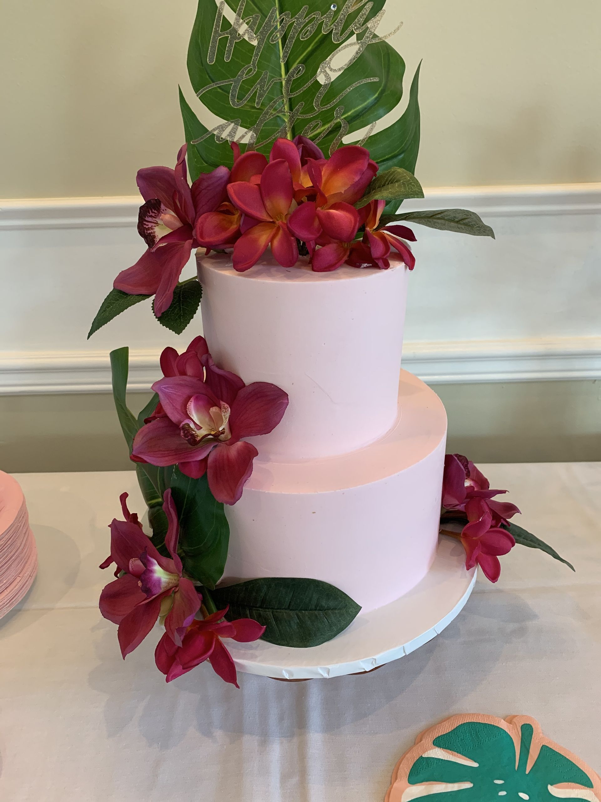 a pink cake with flowers and leaves on it is on a table .