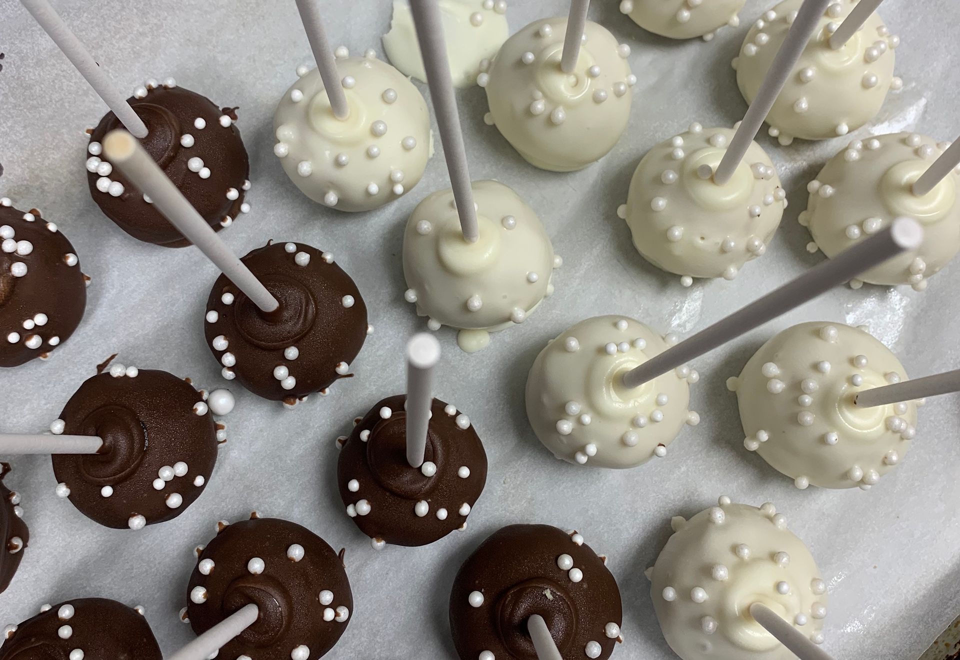 a tray of chocolate and white cake pops with sprinkles