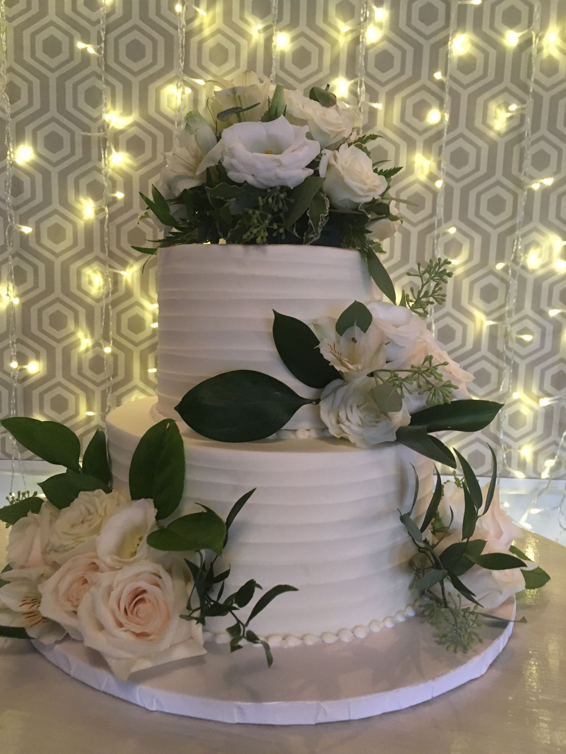 a wedding cake with white roses and green leaves on it