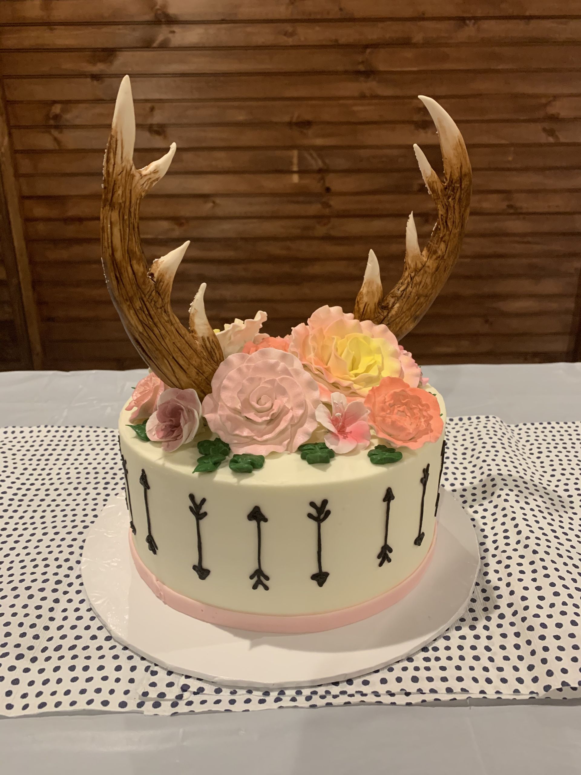 a cake with antlers and flowers on top of it on a table .
