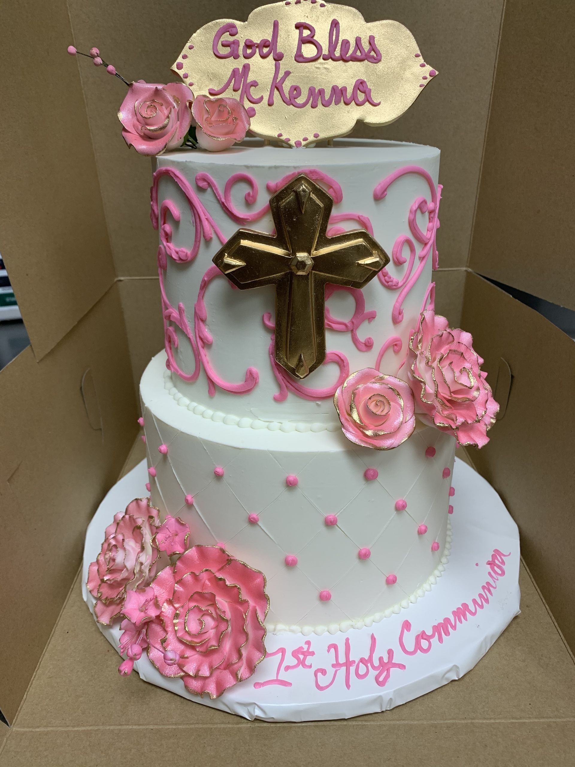 a white cake with pink flowers and a gold cross on top