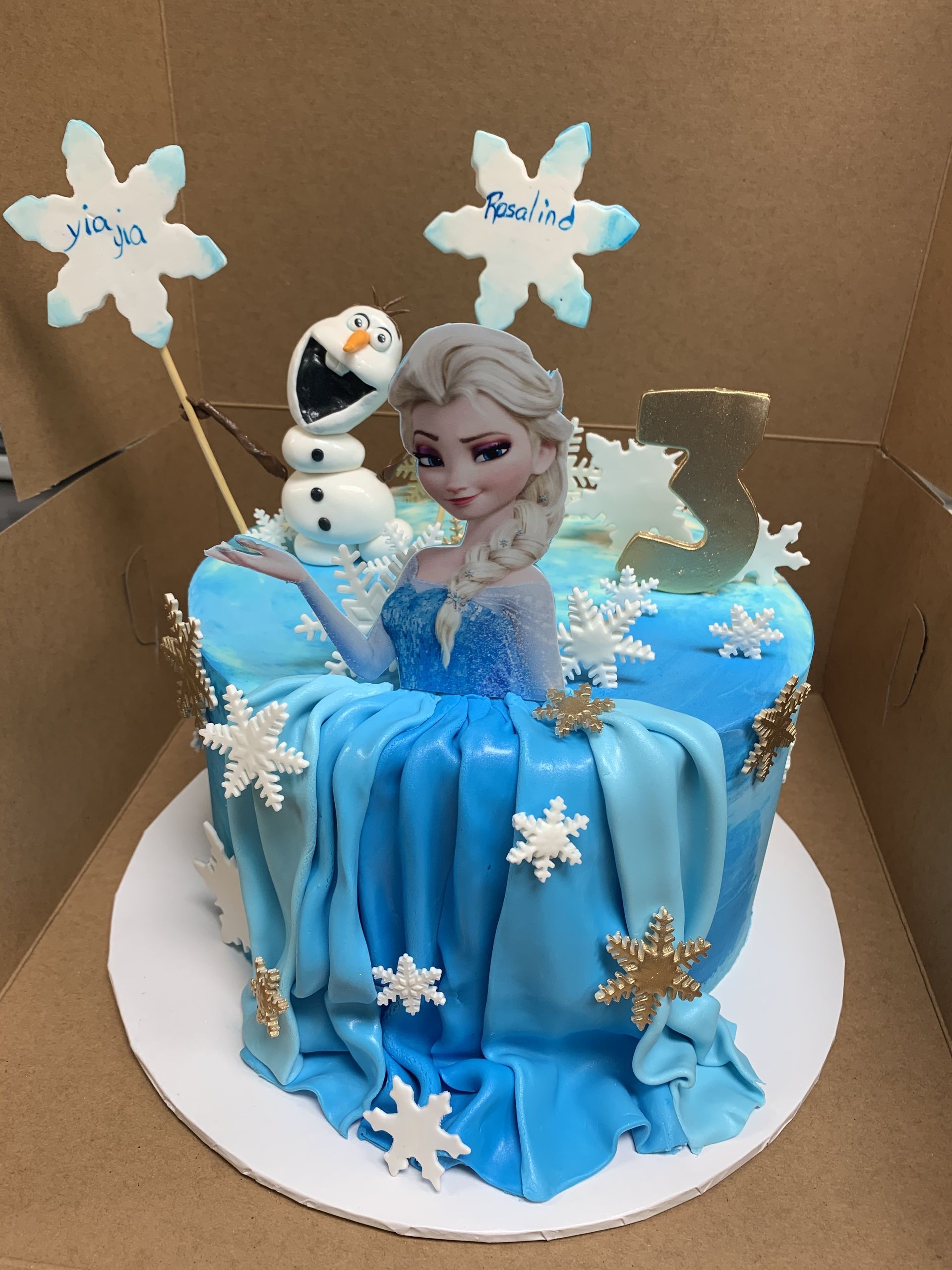 a frozen cake with elsa and olaf on it