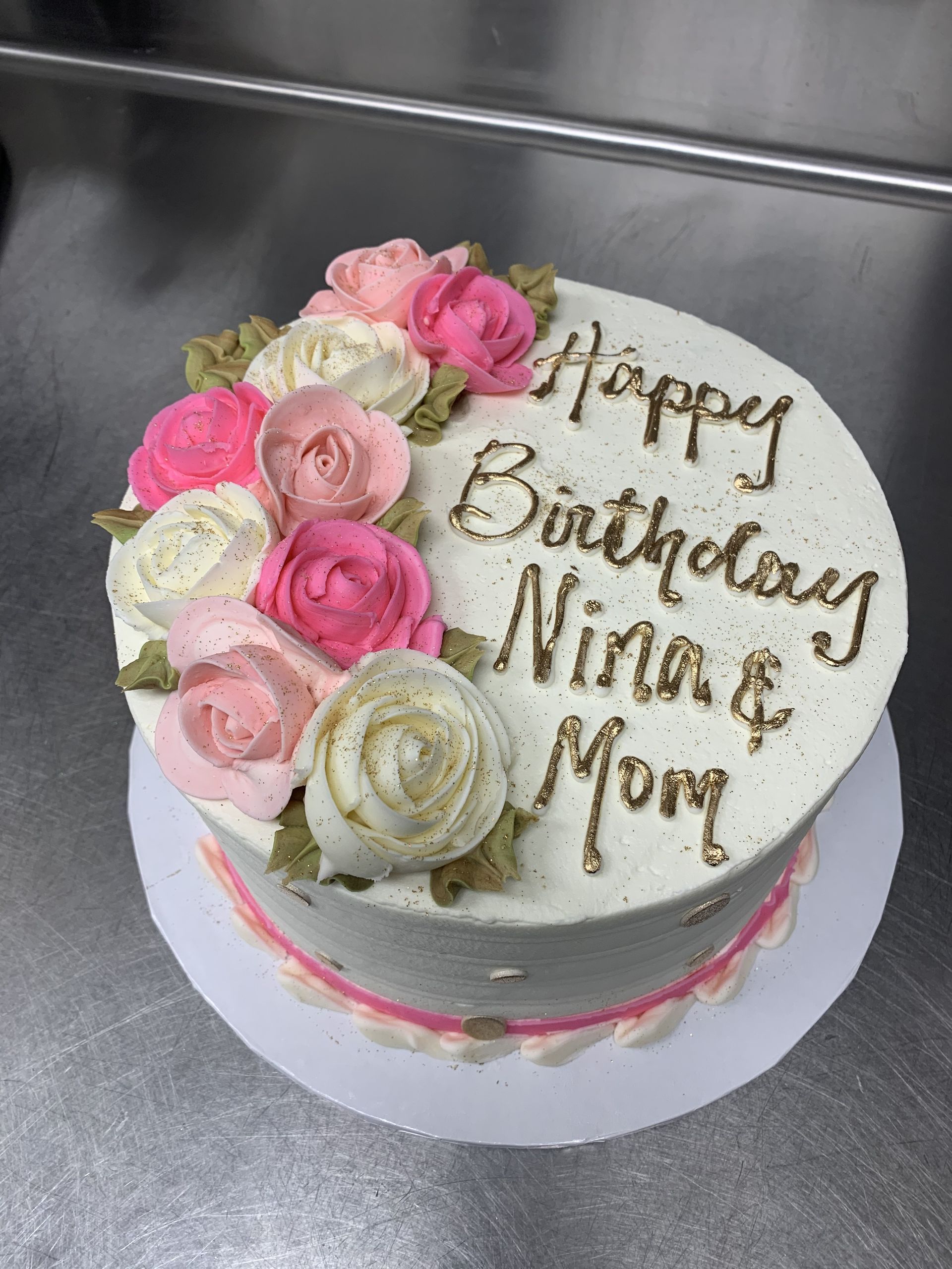 a birthday cake with pink and white roses on it is on a table .