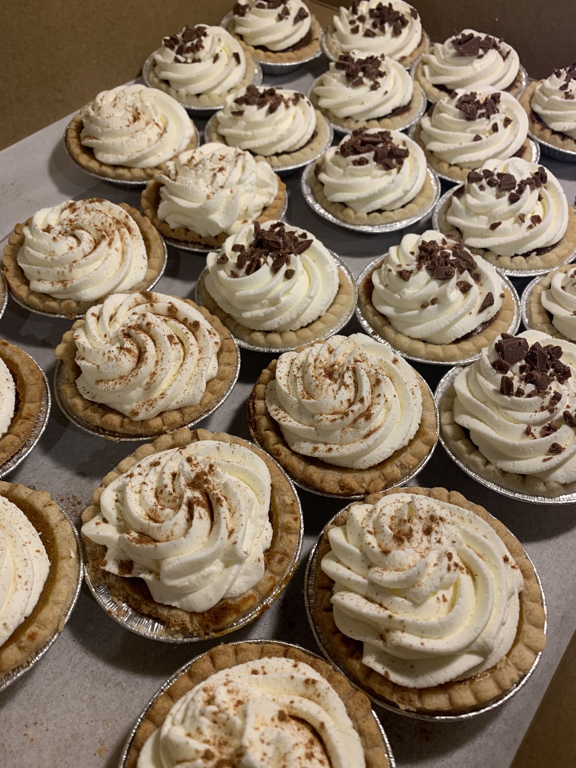 a bunch of mini pies with whipped cream on top