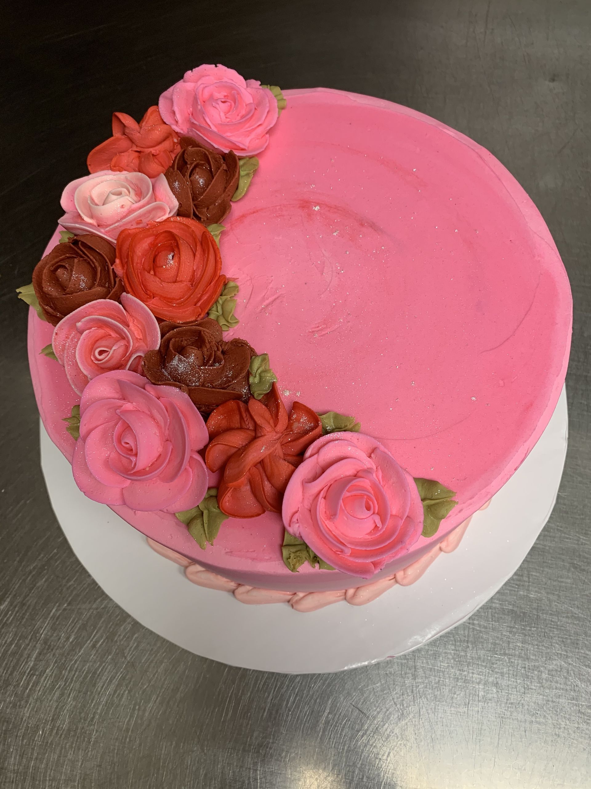 a pink cake with roses on it is sitting on a table .
