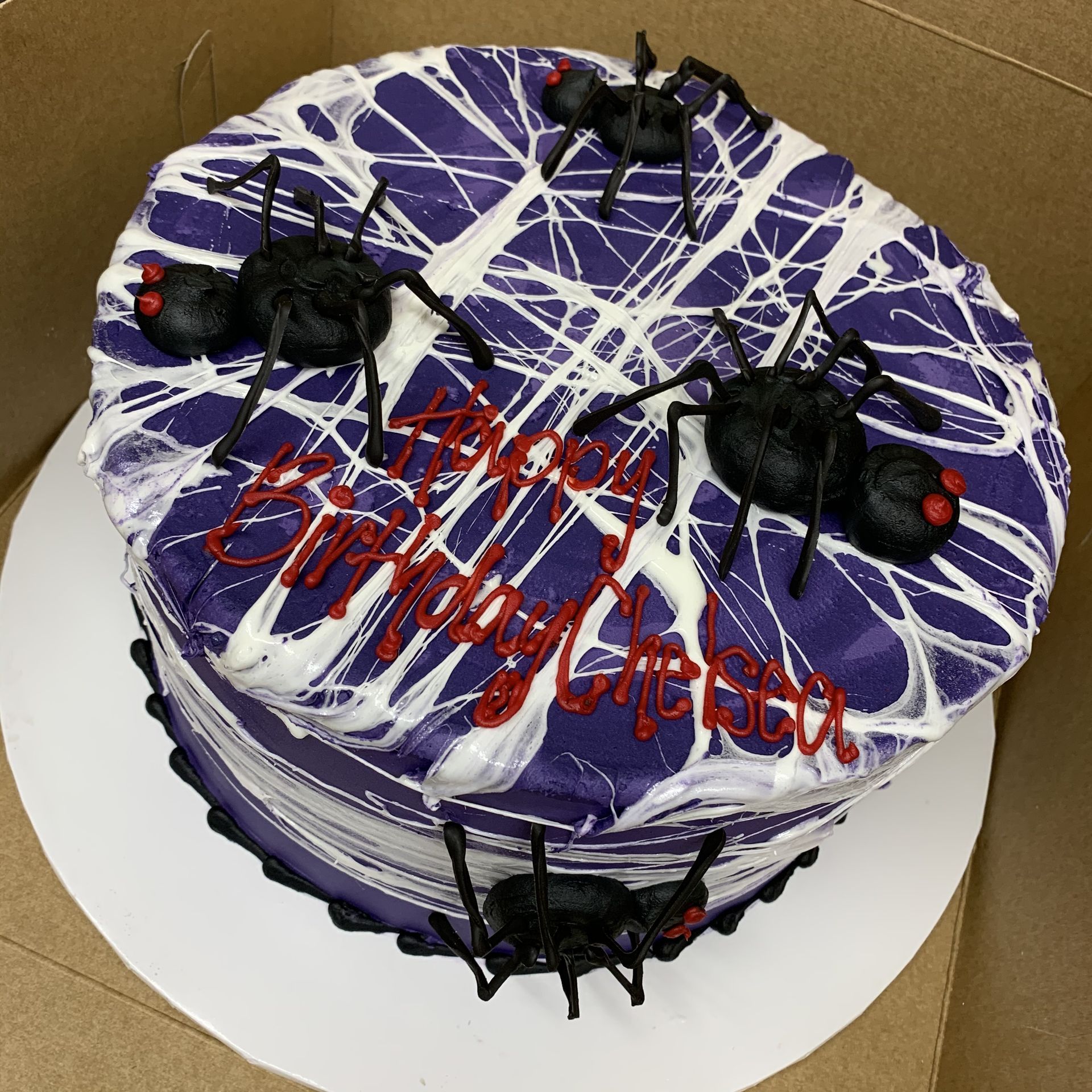 a purple birthday cake with spiders on it
