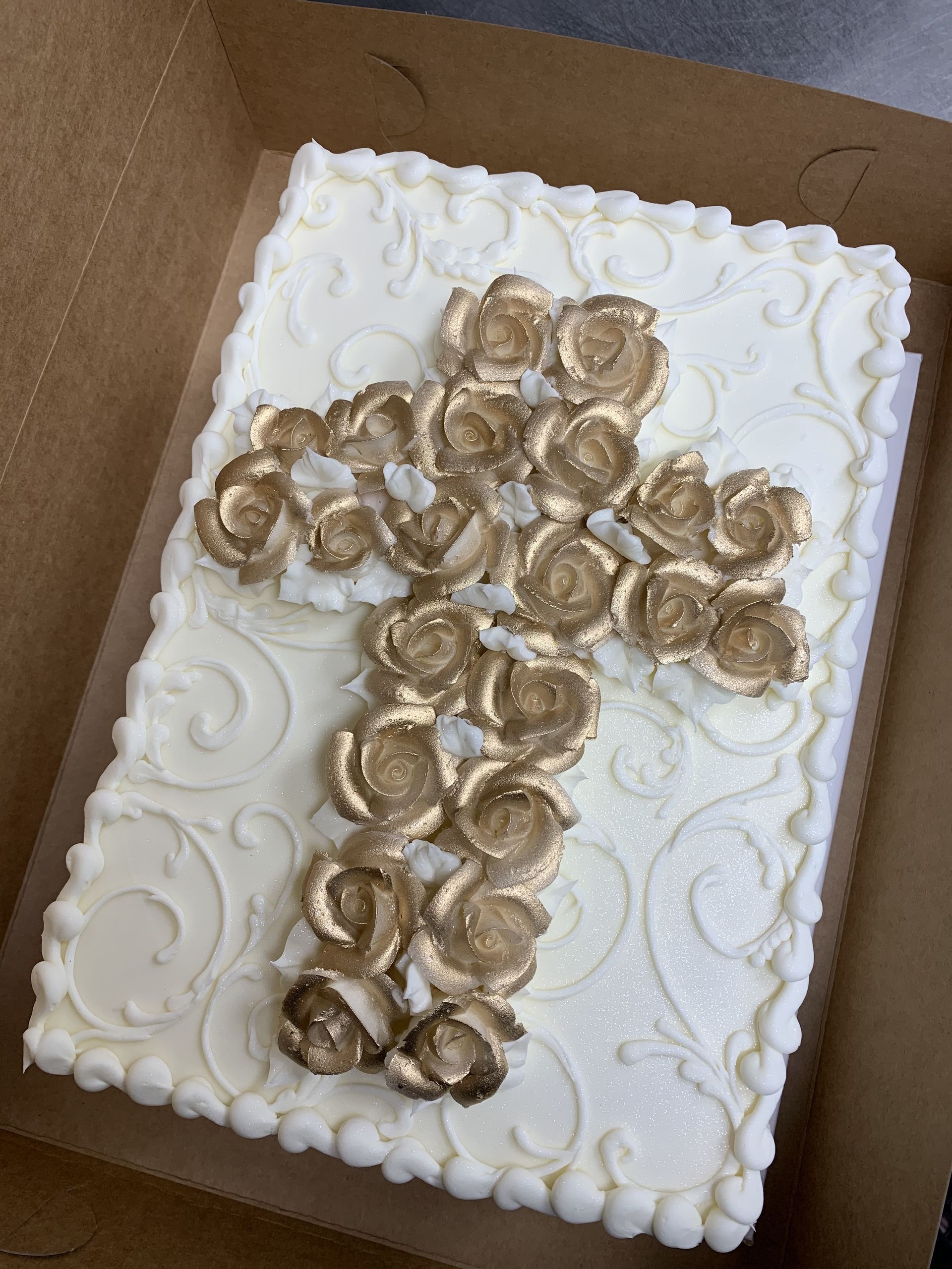 a white cake with a gold cross on it is in a box .