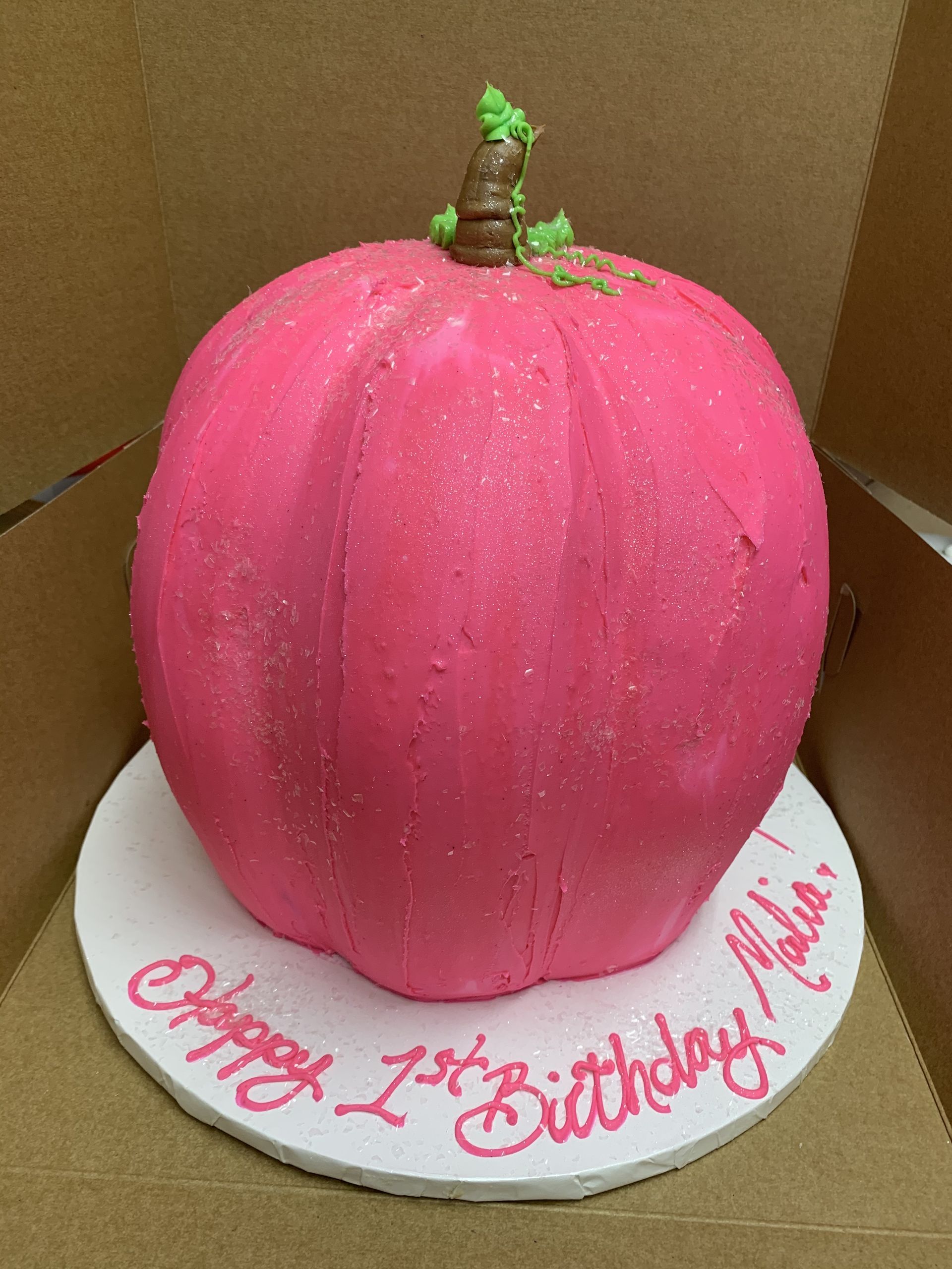 a pink pumpkin cake with the words happy 1st birthday written on it