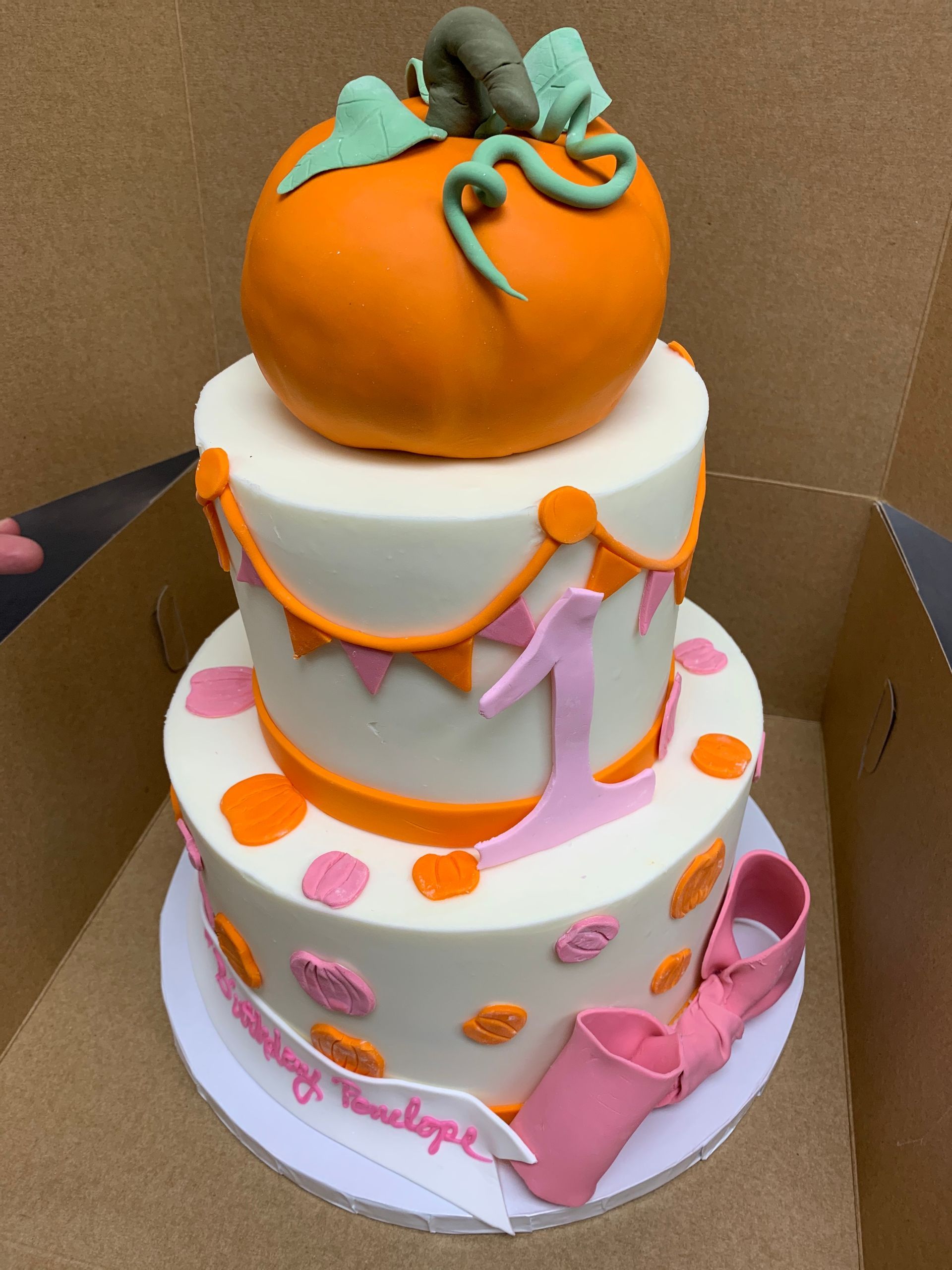 a three tiered cake with a pumpkin on top