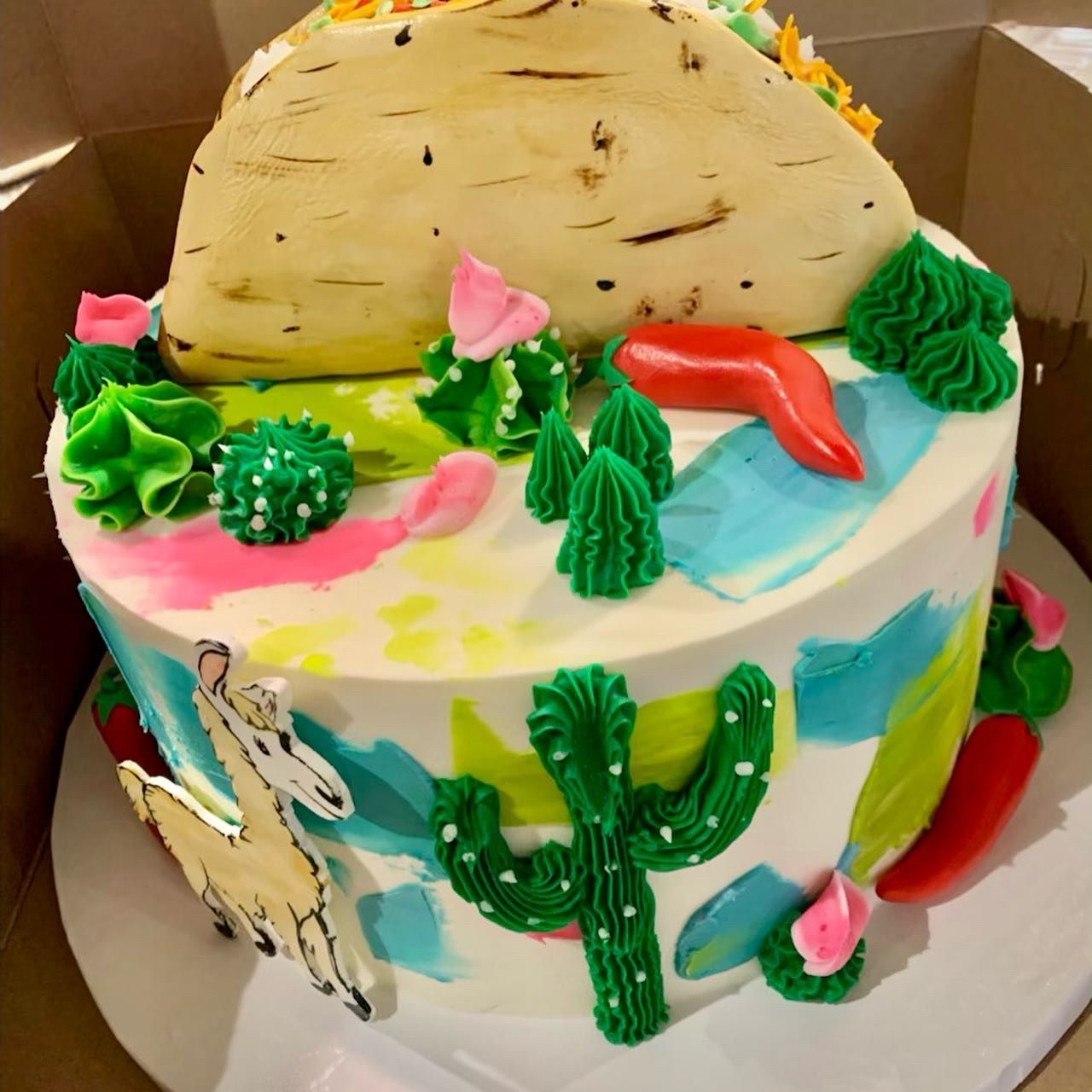 a colorful cake with cactus and a taco on top