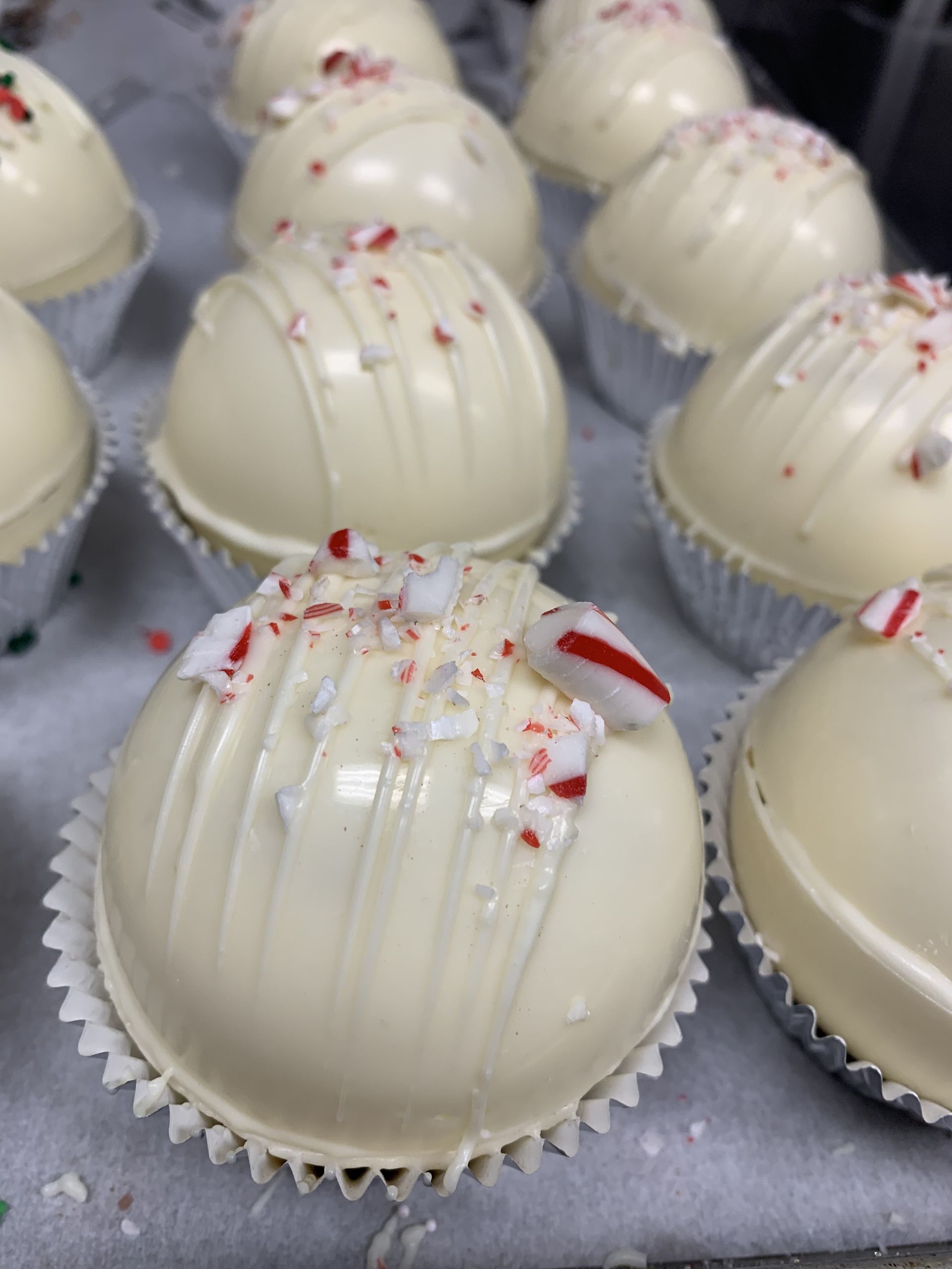 a bunch of white cupcakes with candy canes on top