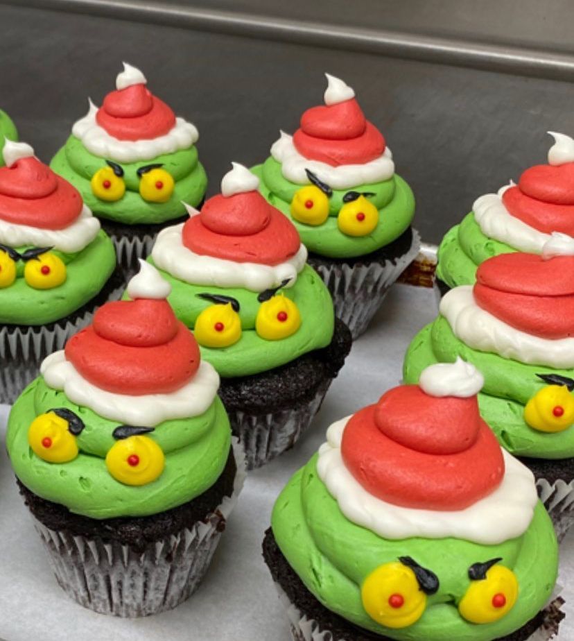 a bunch of cupcakes with green frosting and santa hats on them