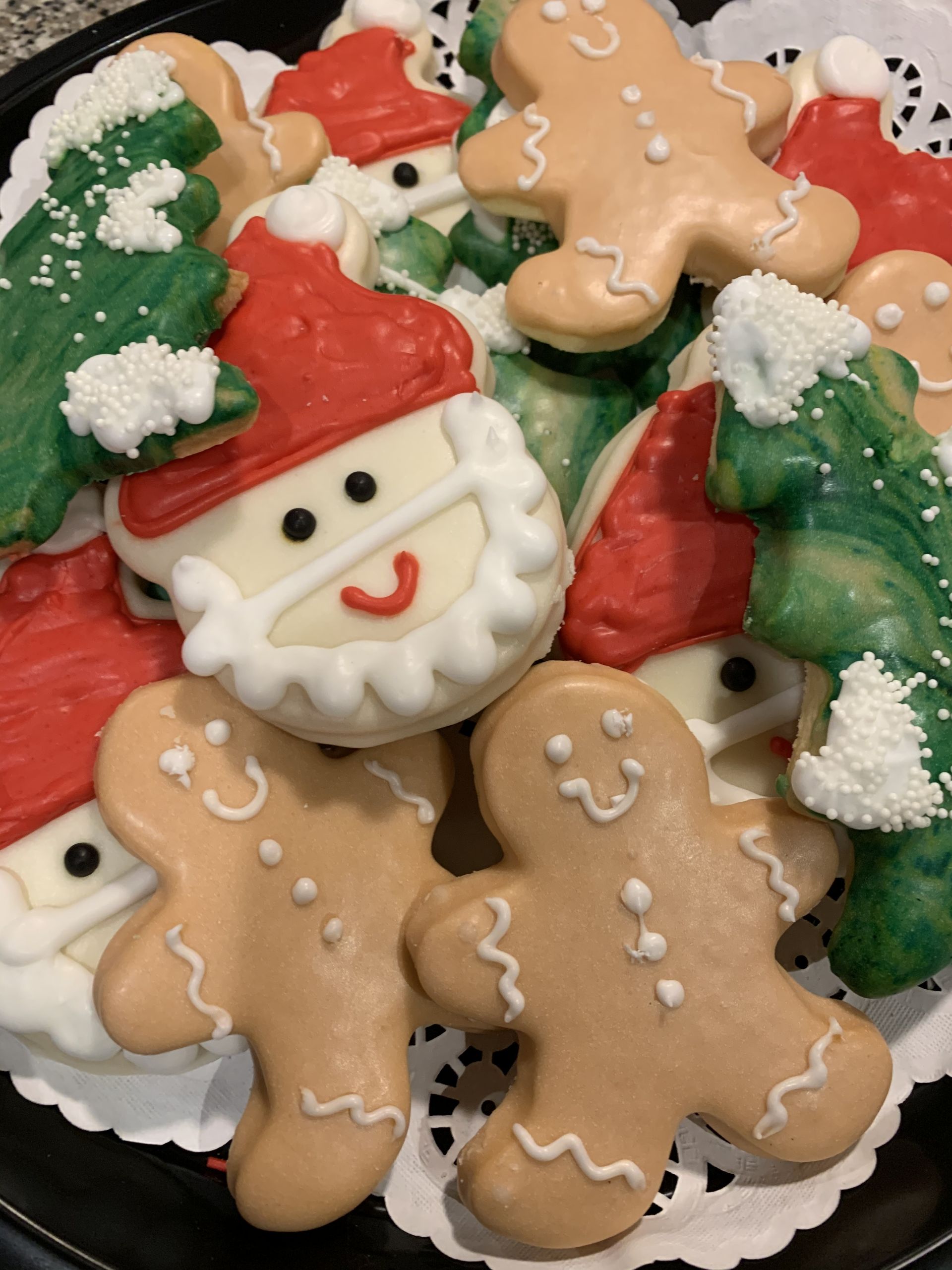 a black plate topped with gingerbread men santa claus and christmas trees