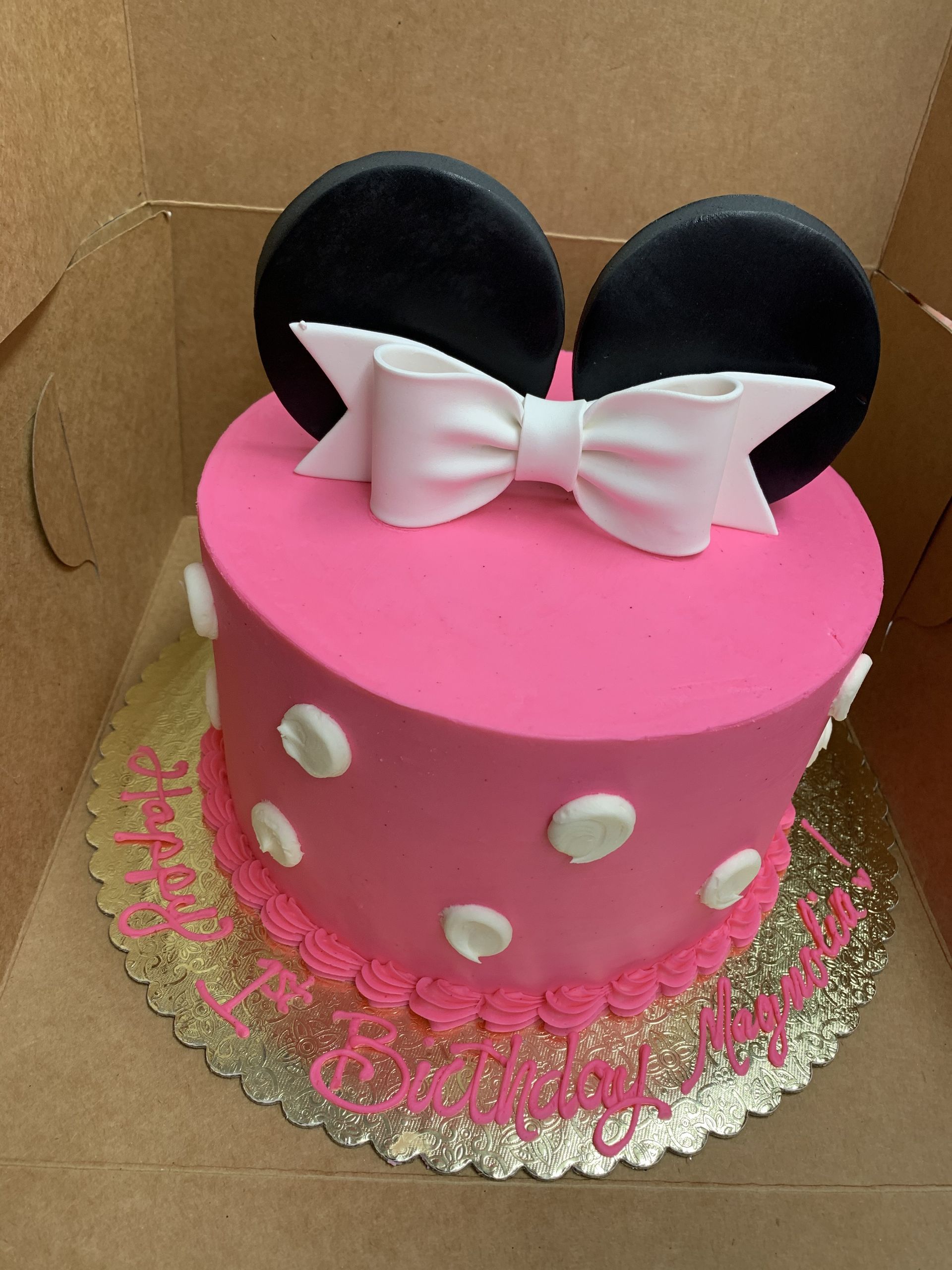 a pink cake with minnie mouse ears and a white bow