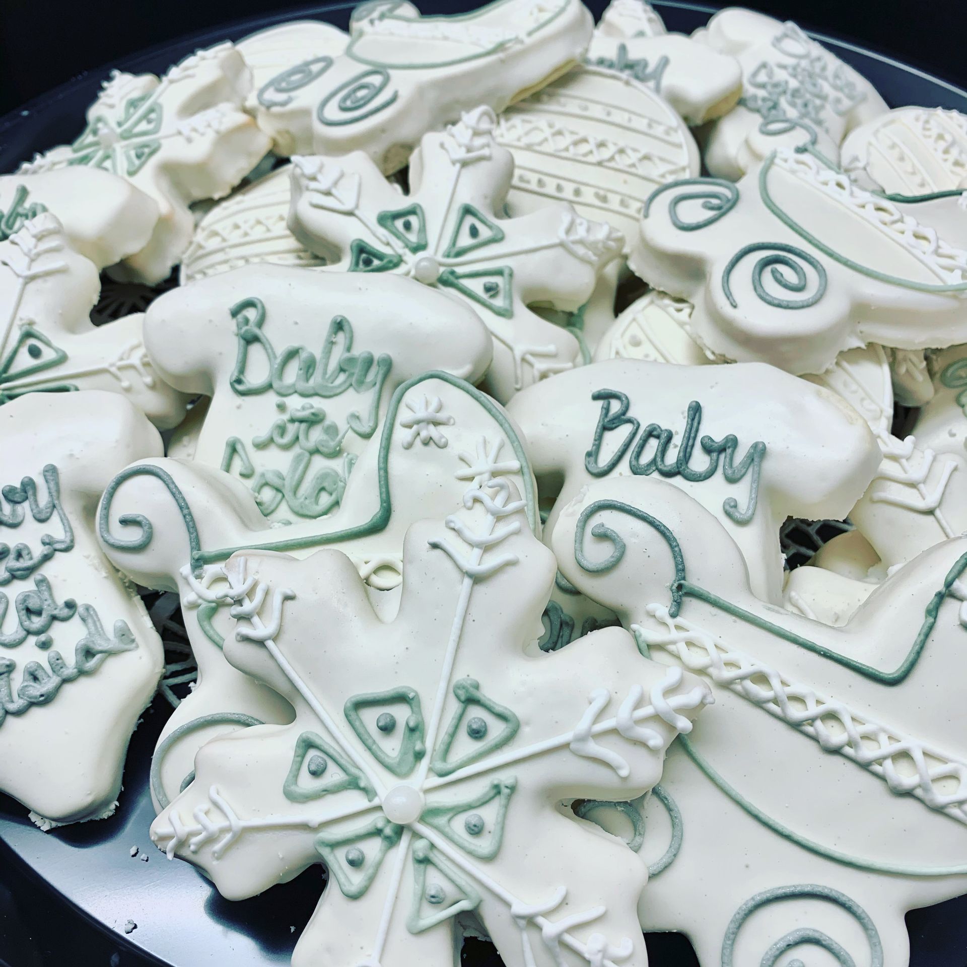 a pile of baby shower cookies on a black plate