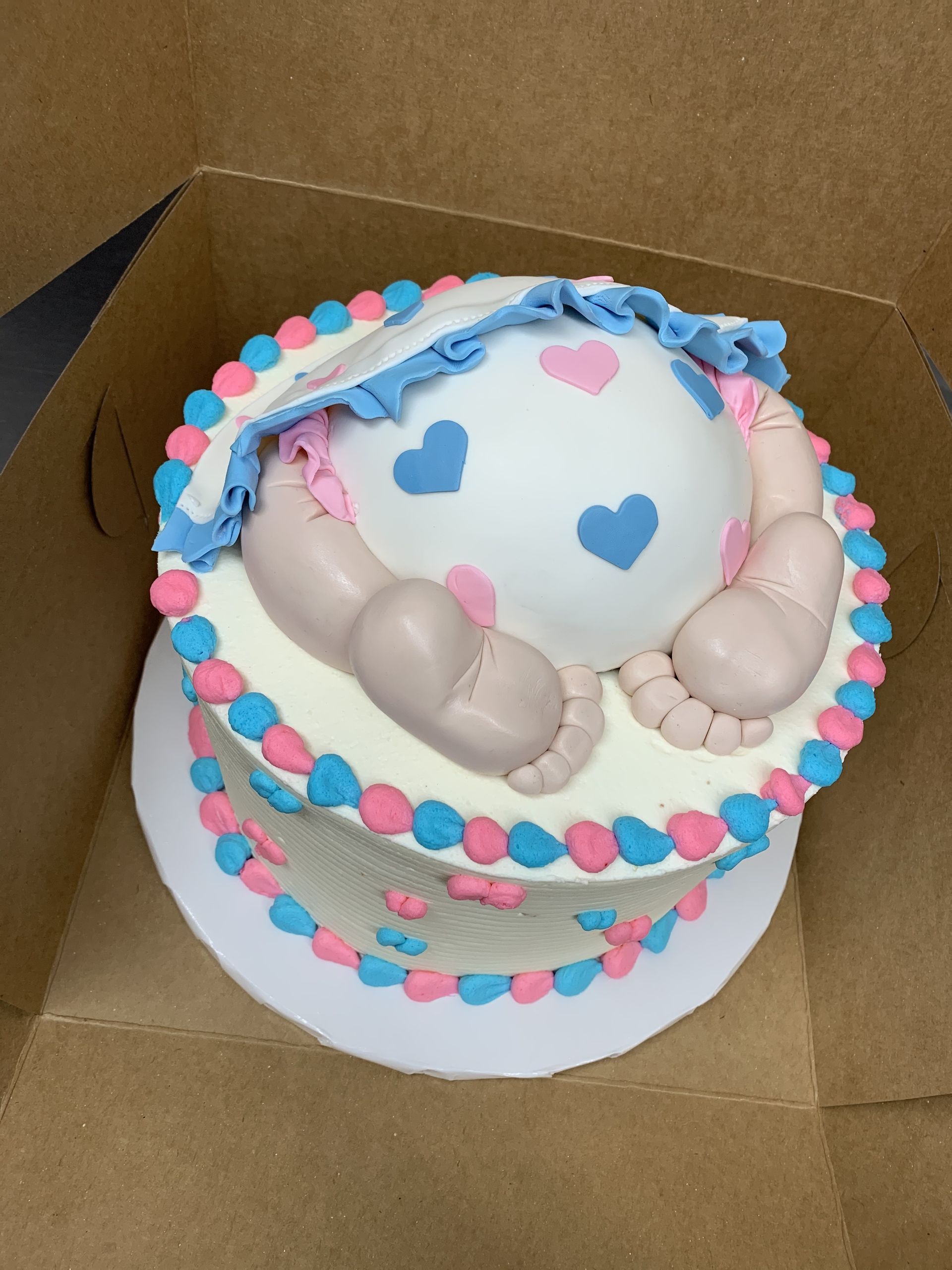 a cake that looks like a baby 's belly is in a box