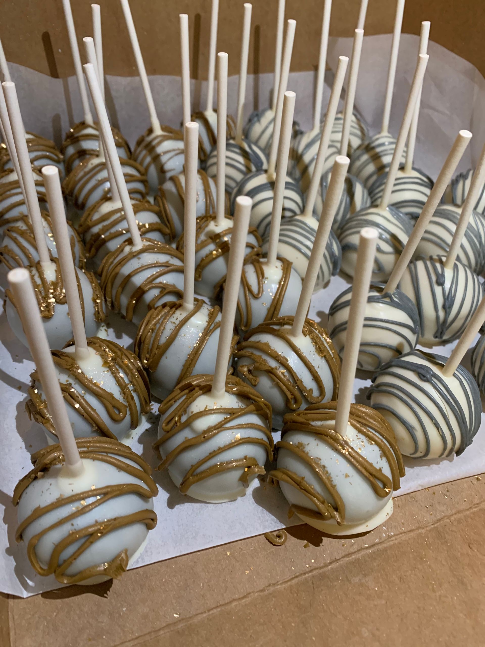 a box filled with white and brown cake pops on sticks .