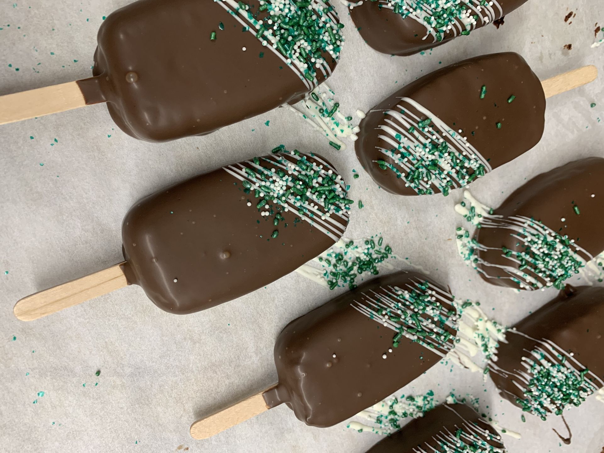 a bunch of chocolate covered ice cream bars with green sprinkles on them