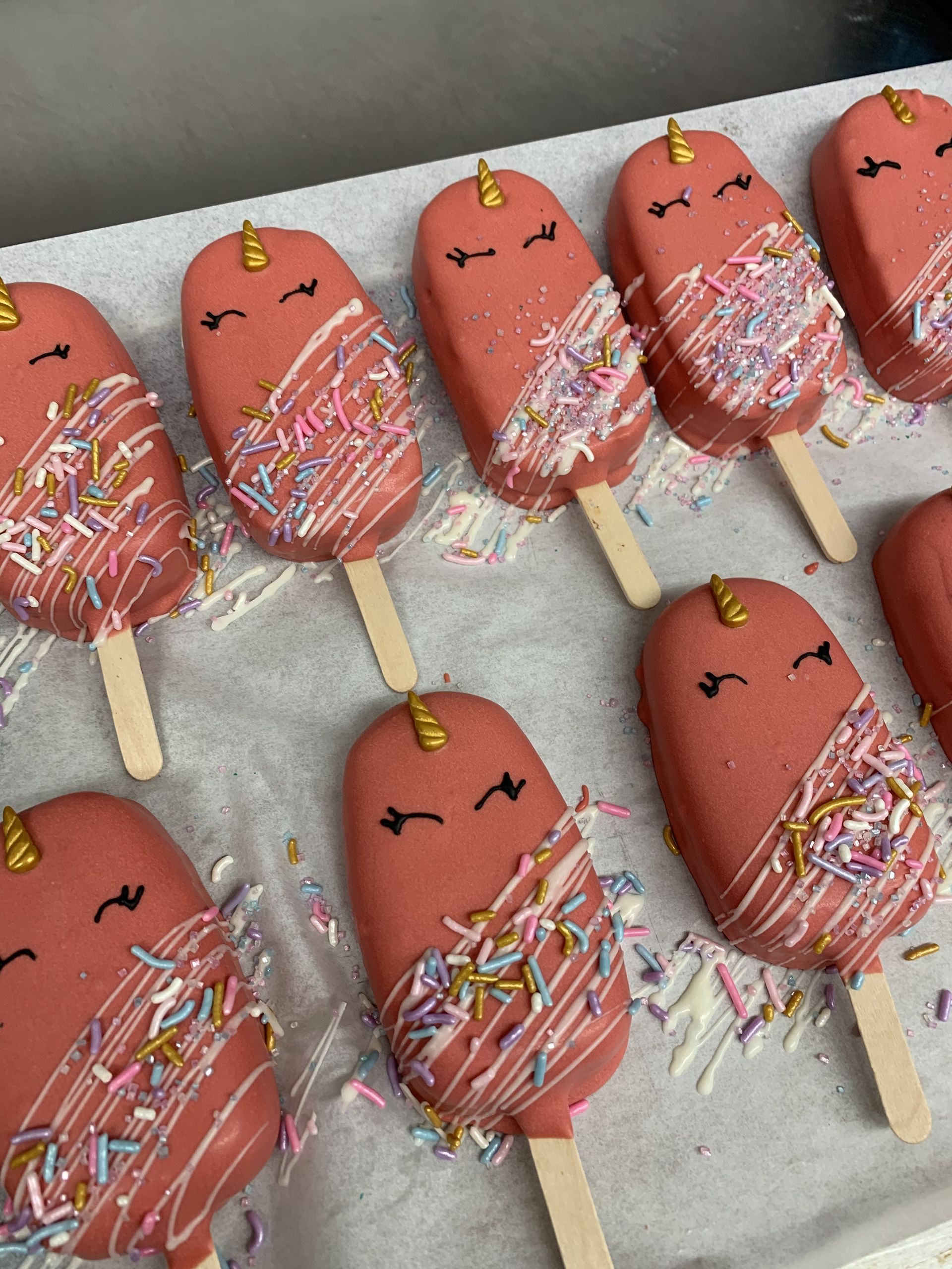 a bunch of pink ice cream pops with sprinkles on them