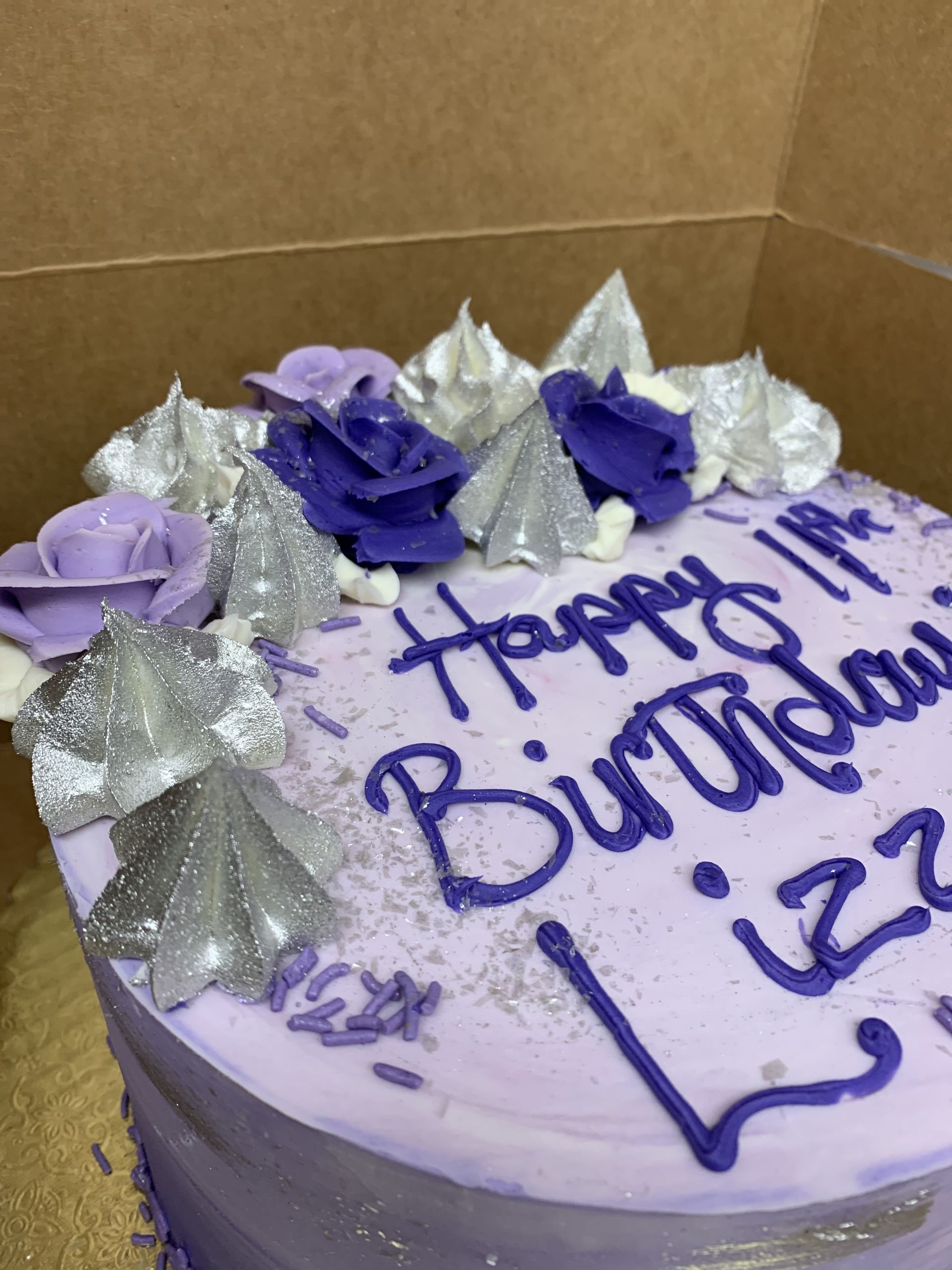 a purple birthday cake with purple frosting and silver sprinkles