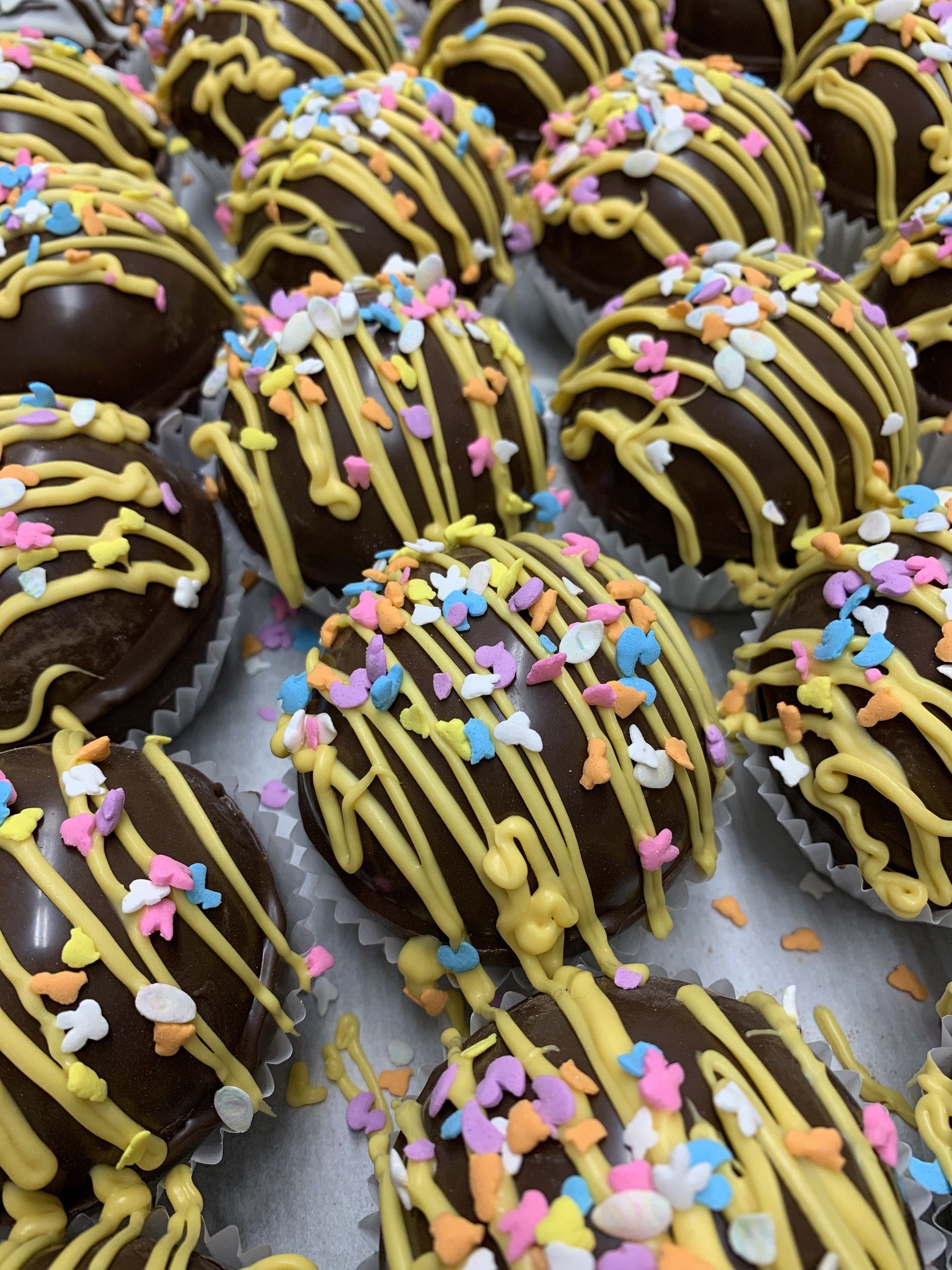 a bunch of chocolate covered cupcakes with yellow frosting and sprinkles