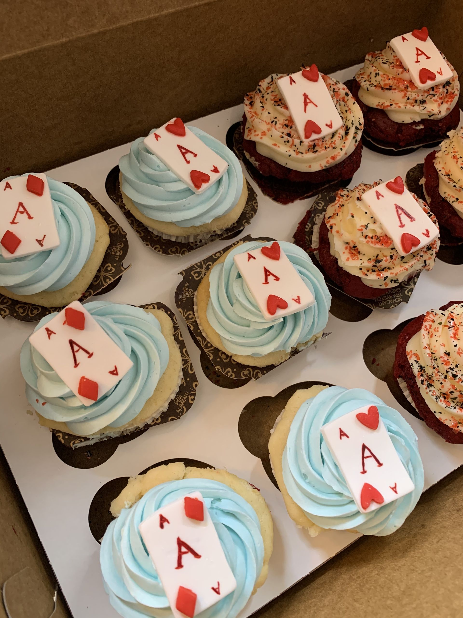 a box of cupcakes with playing cards on them