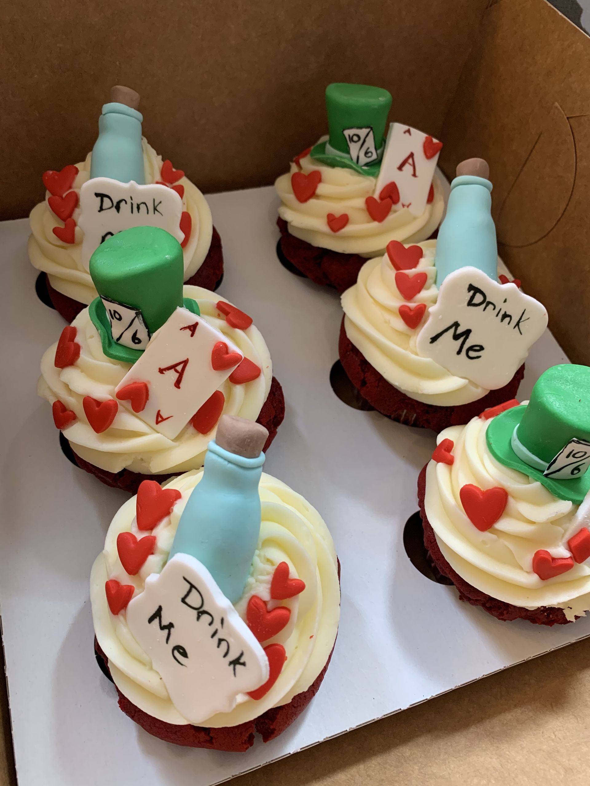 a box of alice in wonderland themed cupcakes