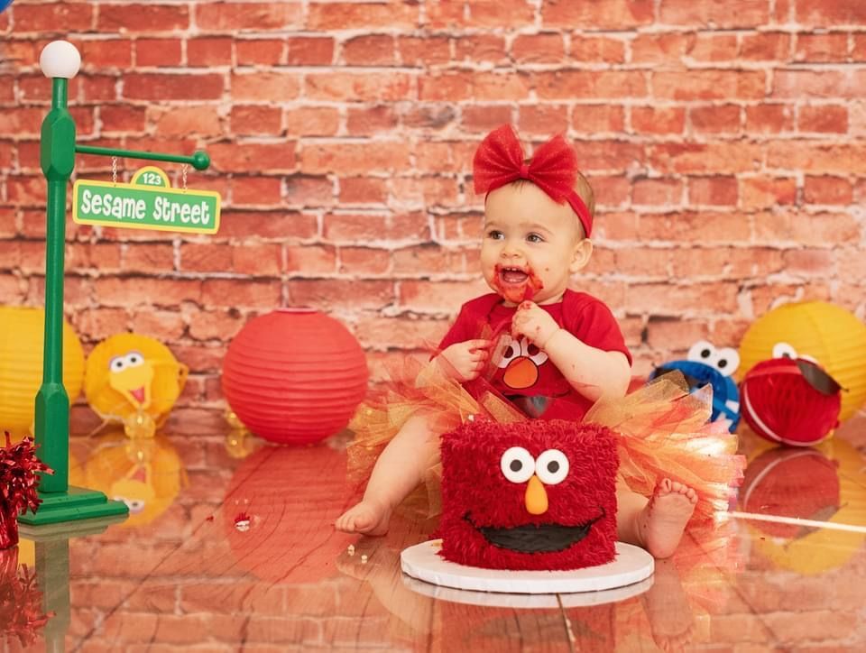 a baby is sitting in front of a sesame street cake .
