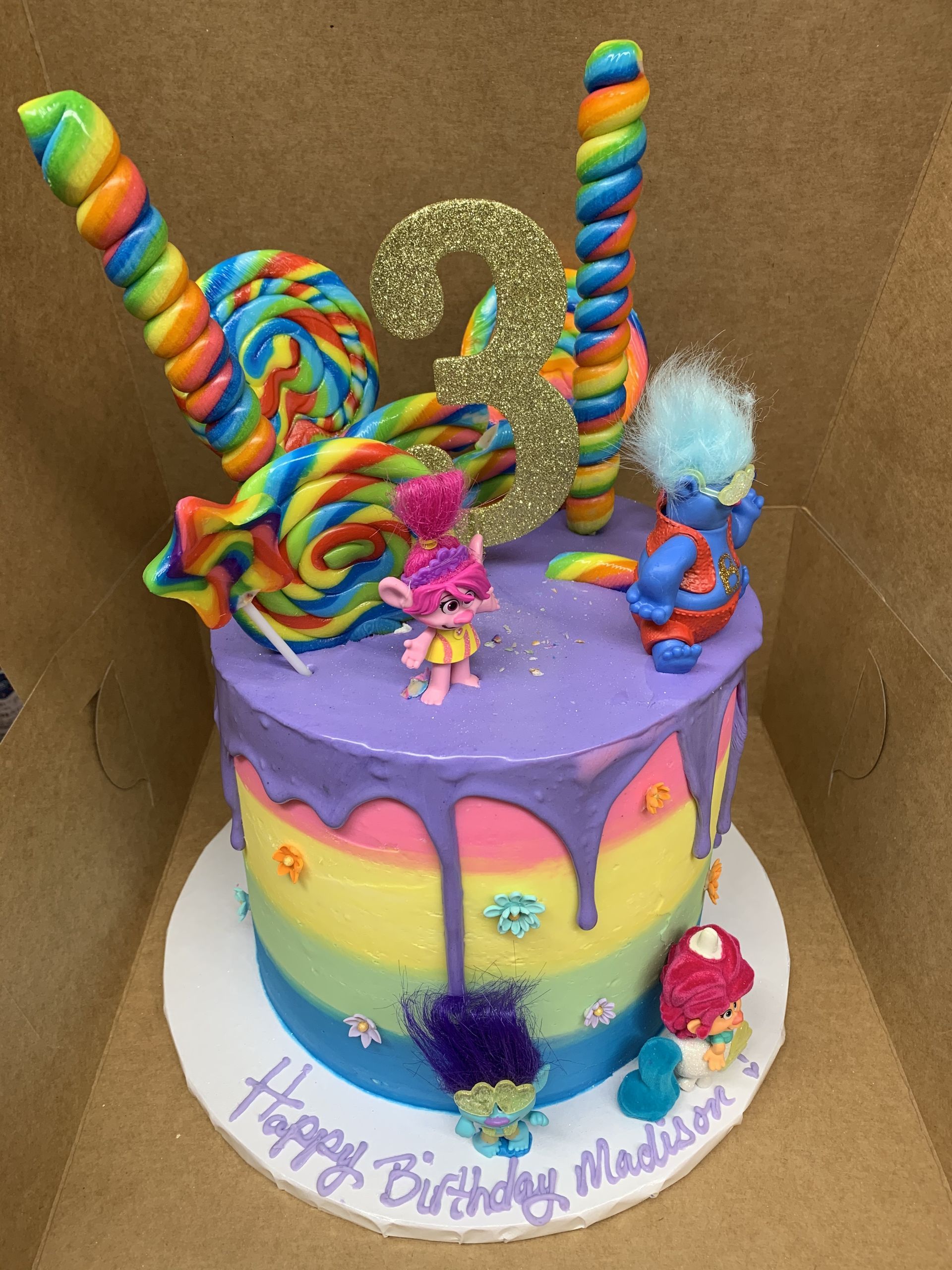 a birthday cake with trolls and lollipops on it