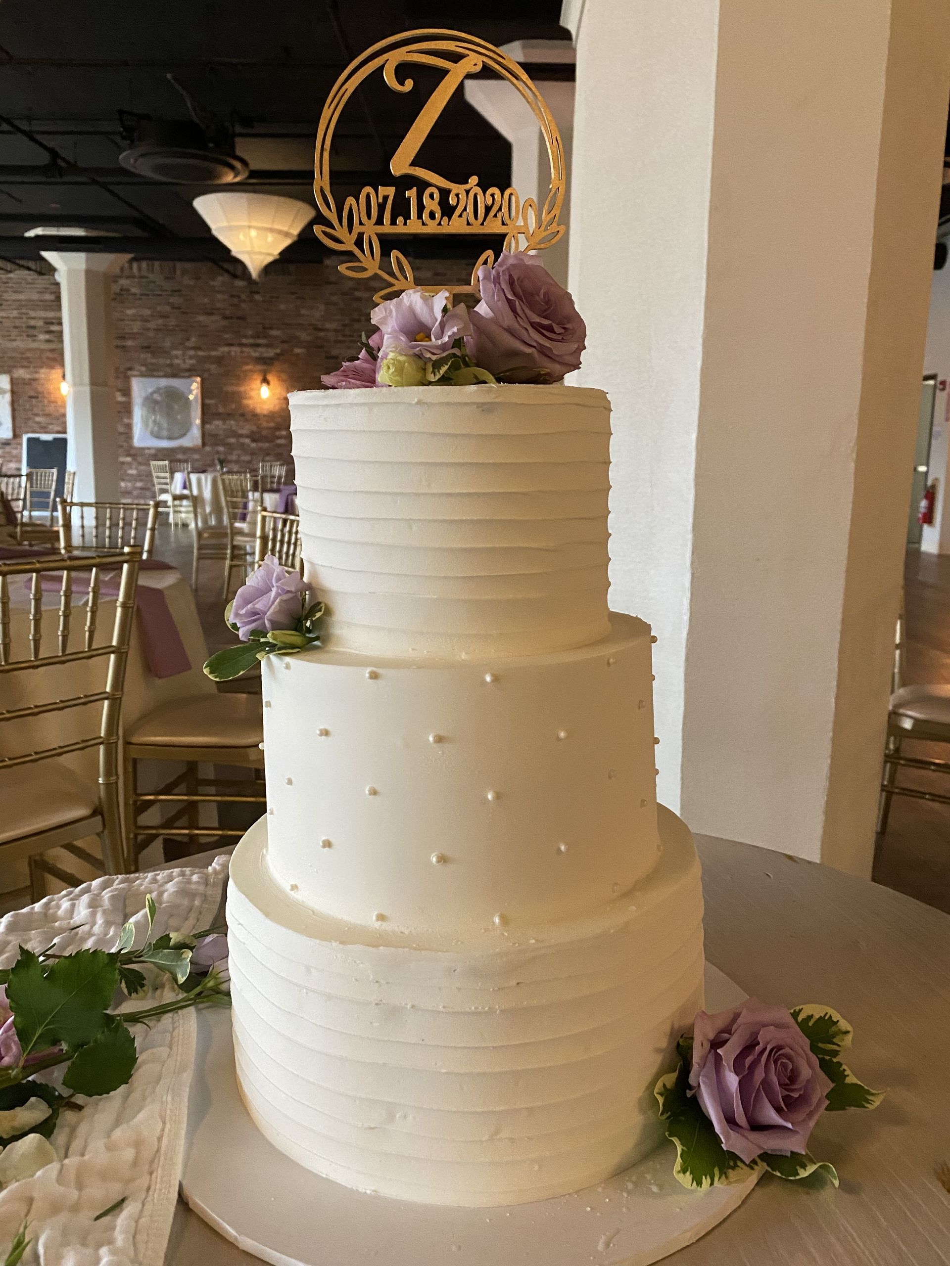 a white wedding cake with purple flowers on top is sitting on a table .