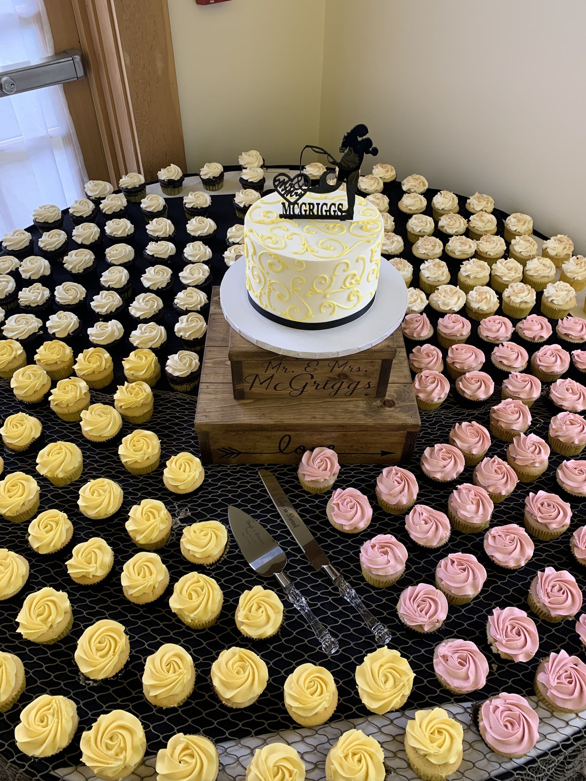 a table topped with lots of cupcakes and a cake .