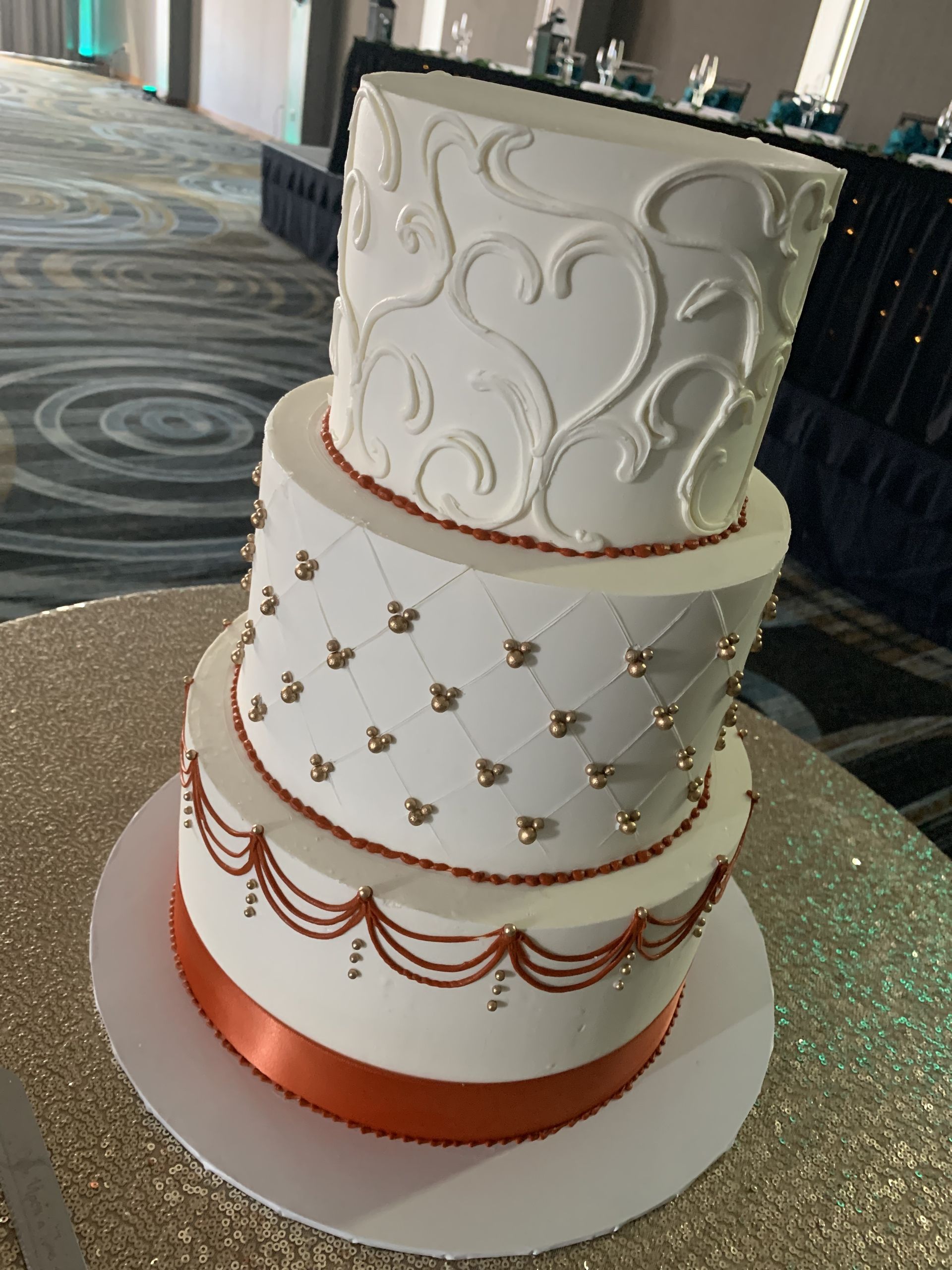 a white wedding cake with a red ribbon is on a table