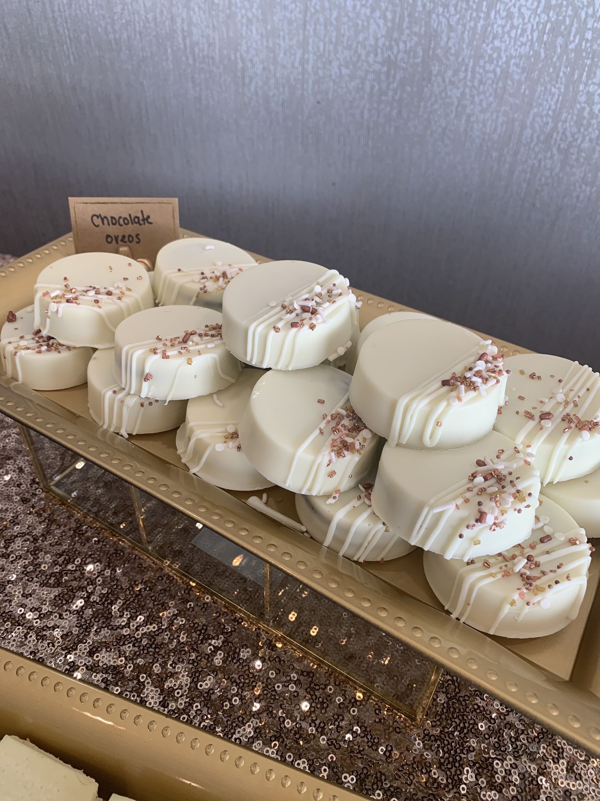 a tray of white chocolate covered cookies with pink sprinkles on a table .
