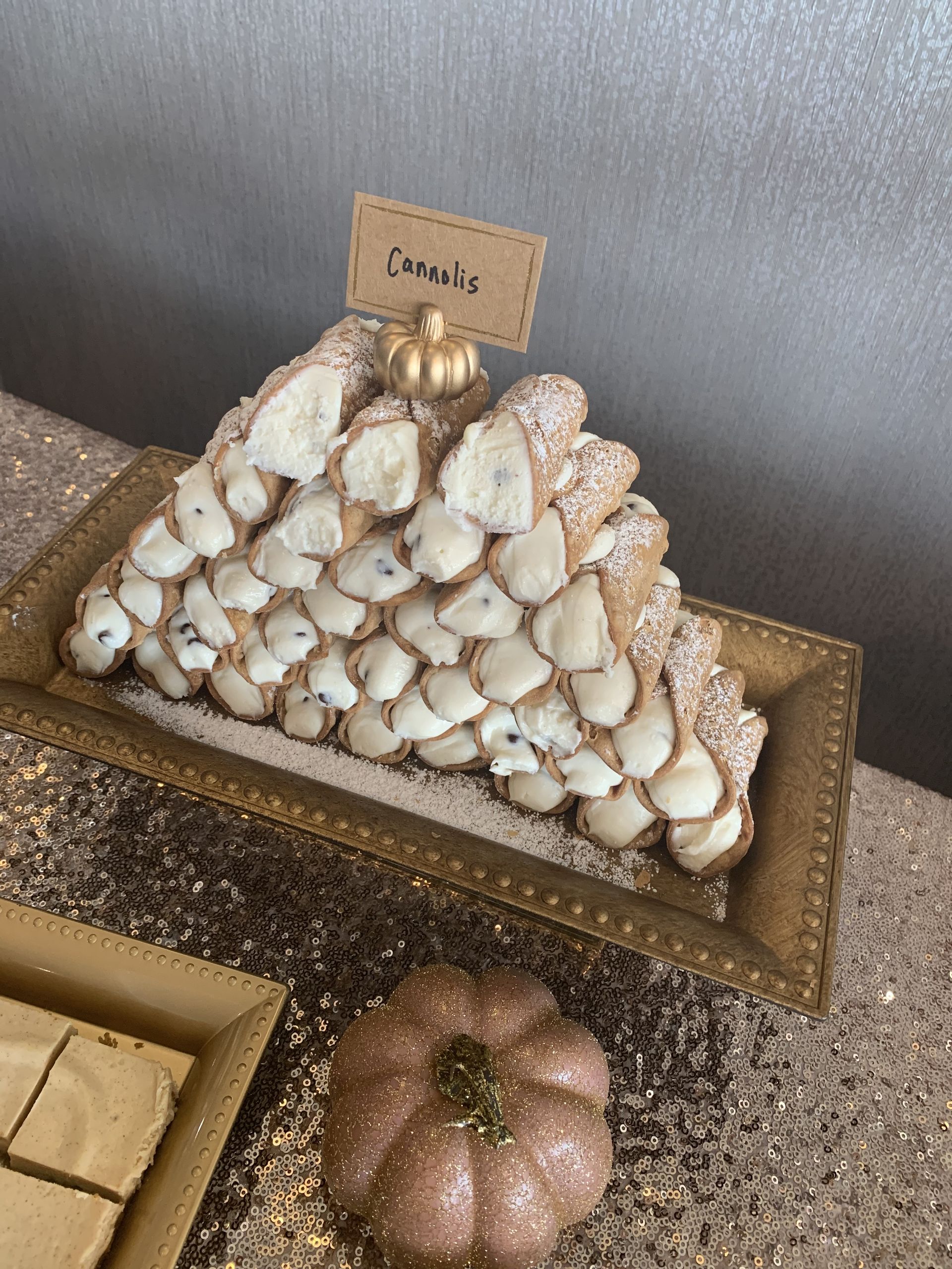 a pyramid of cannoli on a gold plate on a table .
