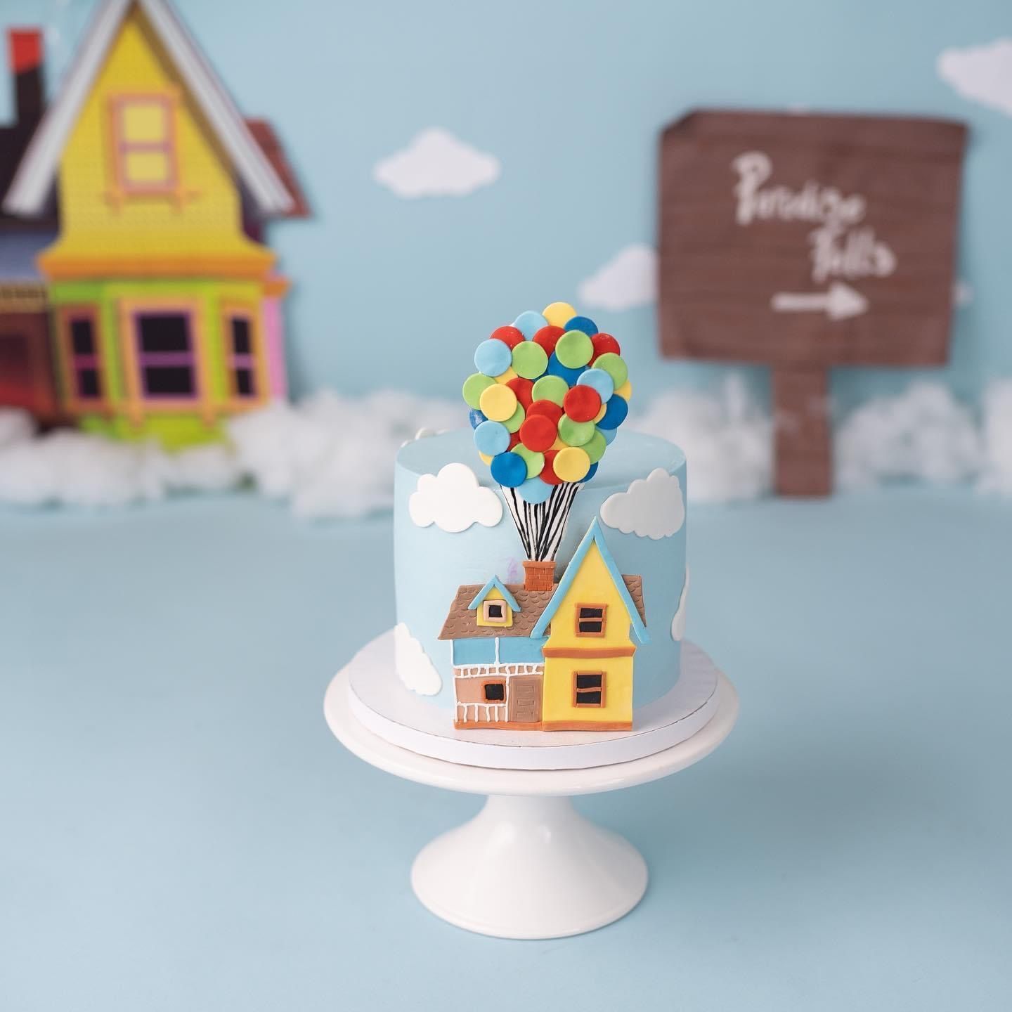 a cake with a house and balloons on it