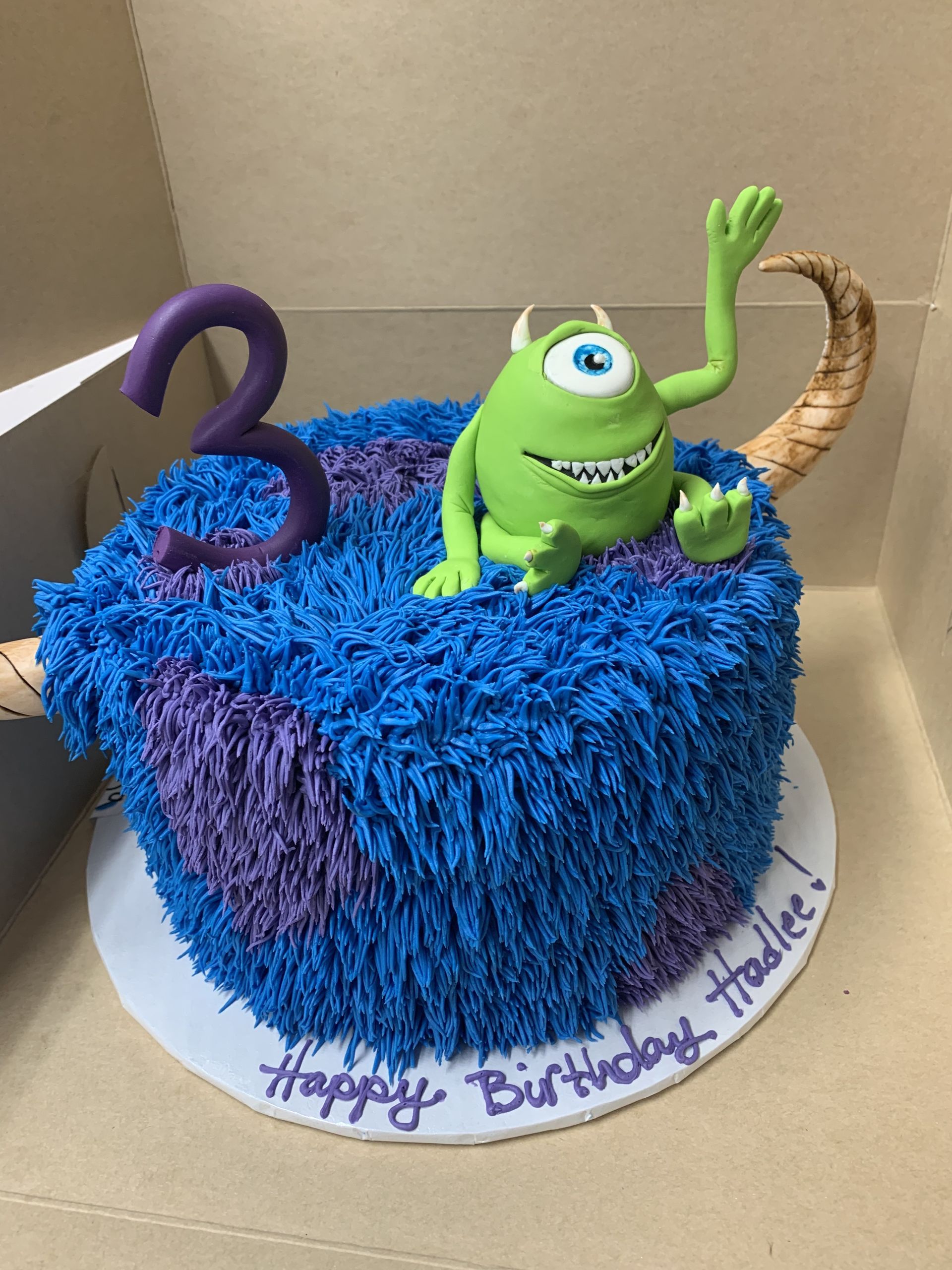 a birthday cake with a monster on top and the number 3 on it