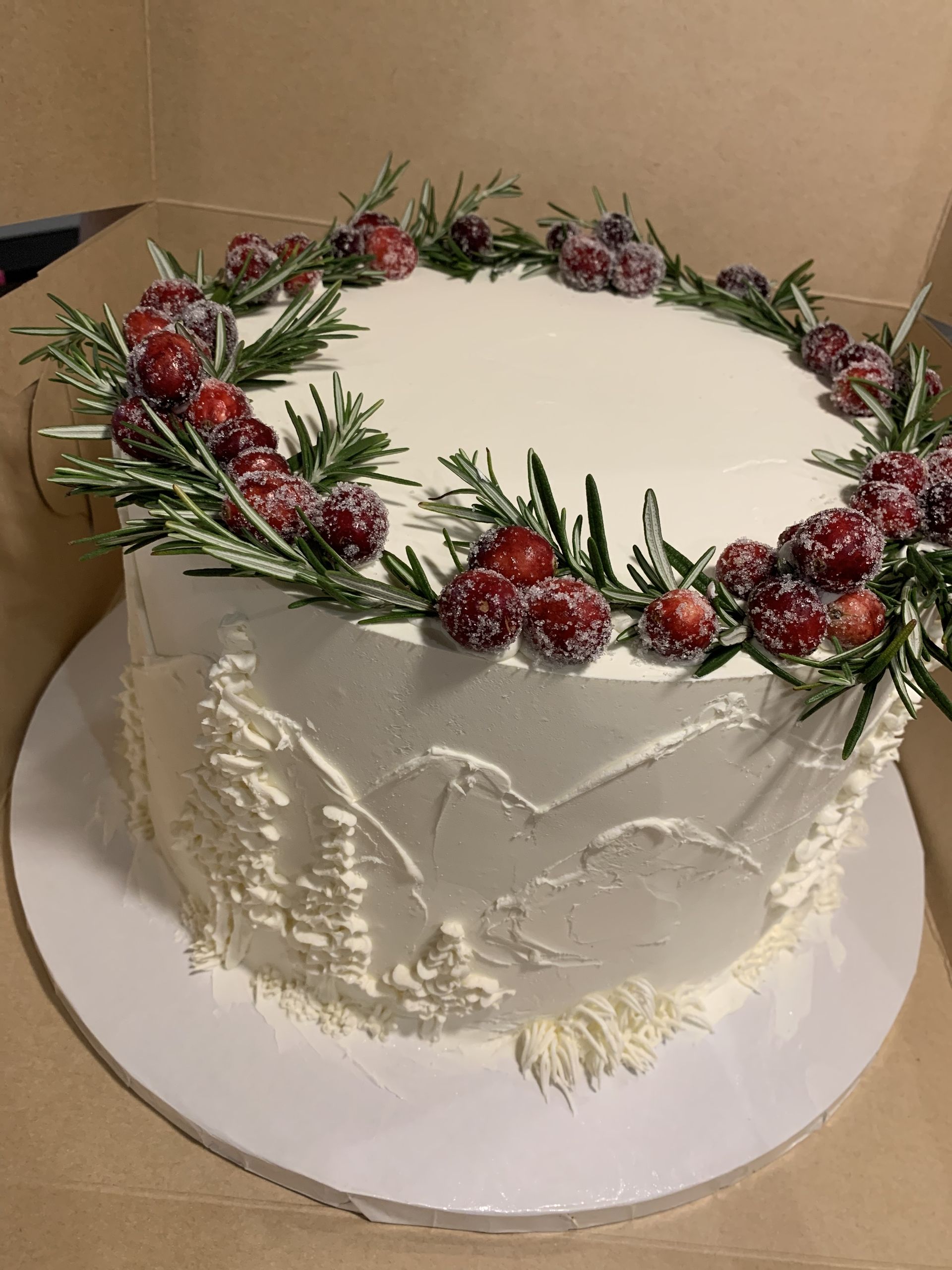 a white cake with cranberries and rosemary on top .