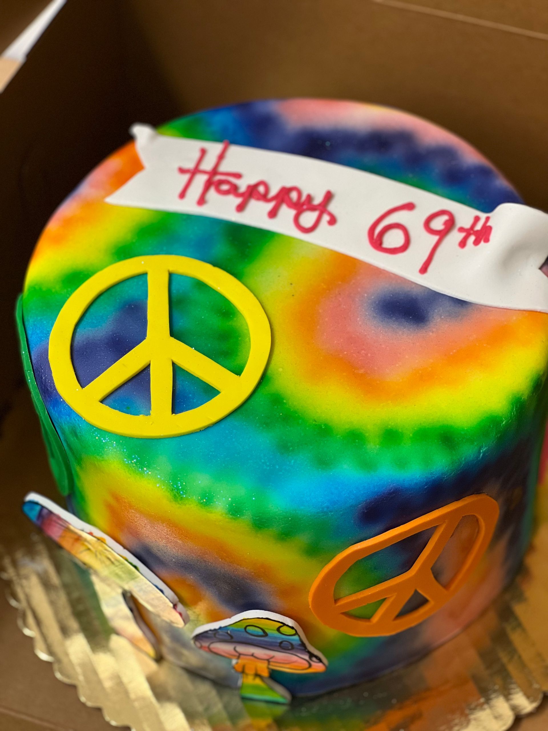 a tie dye birthday cake with a peace sign on it