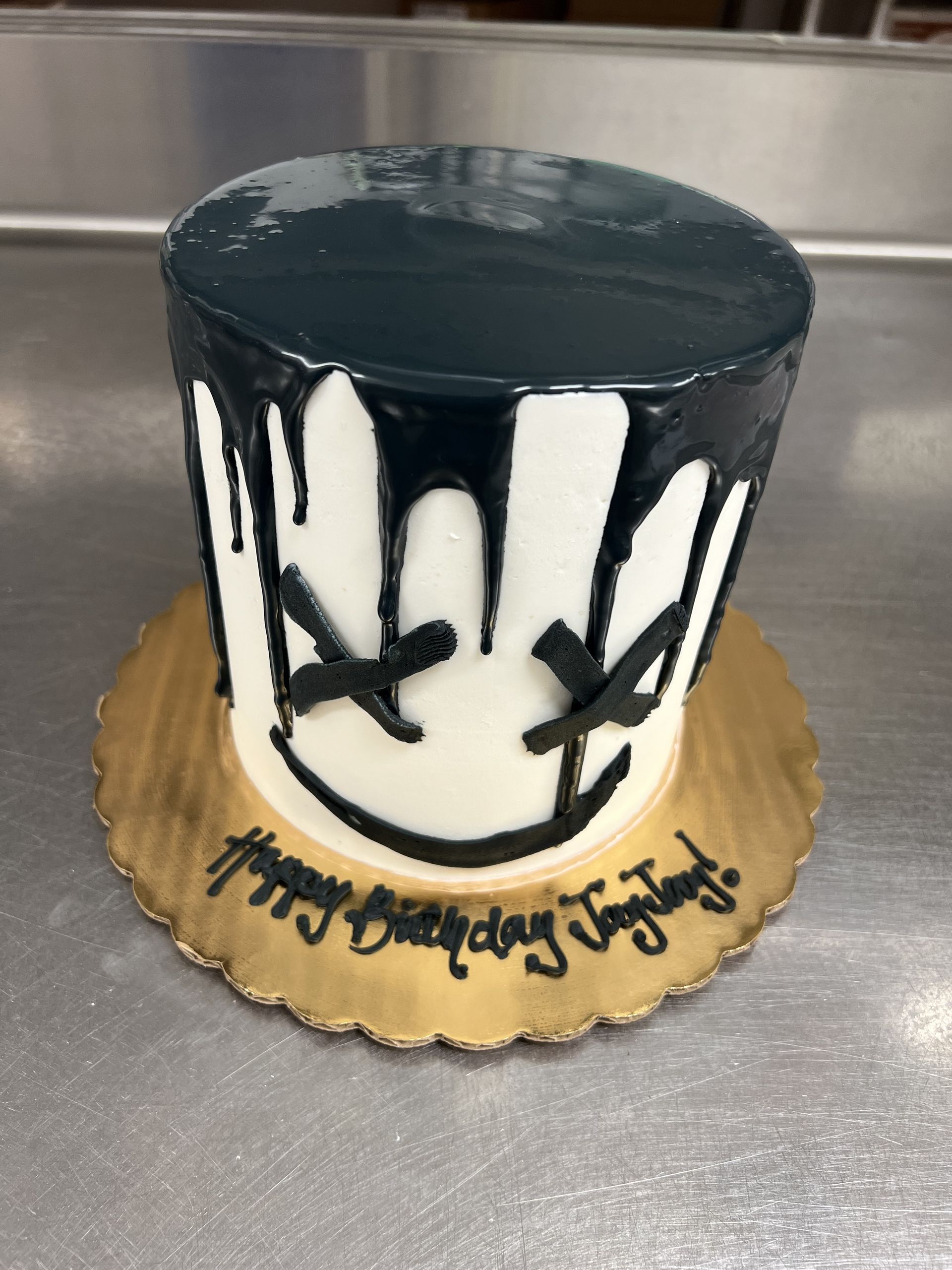 a black and white birthday cake with a smiley face on it