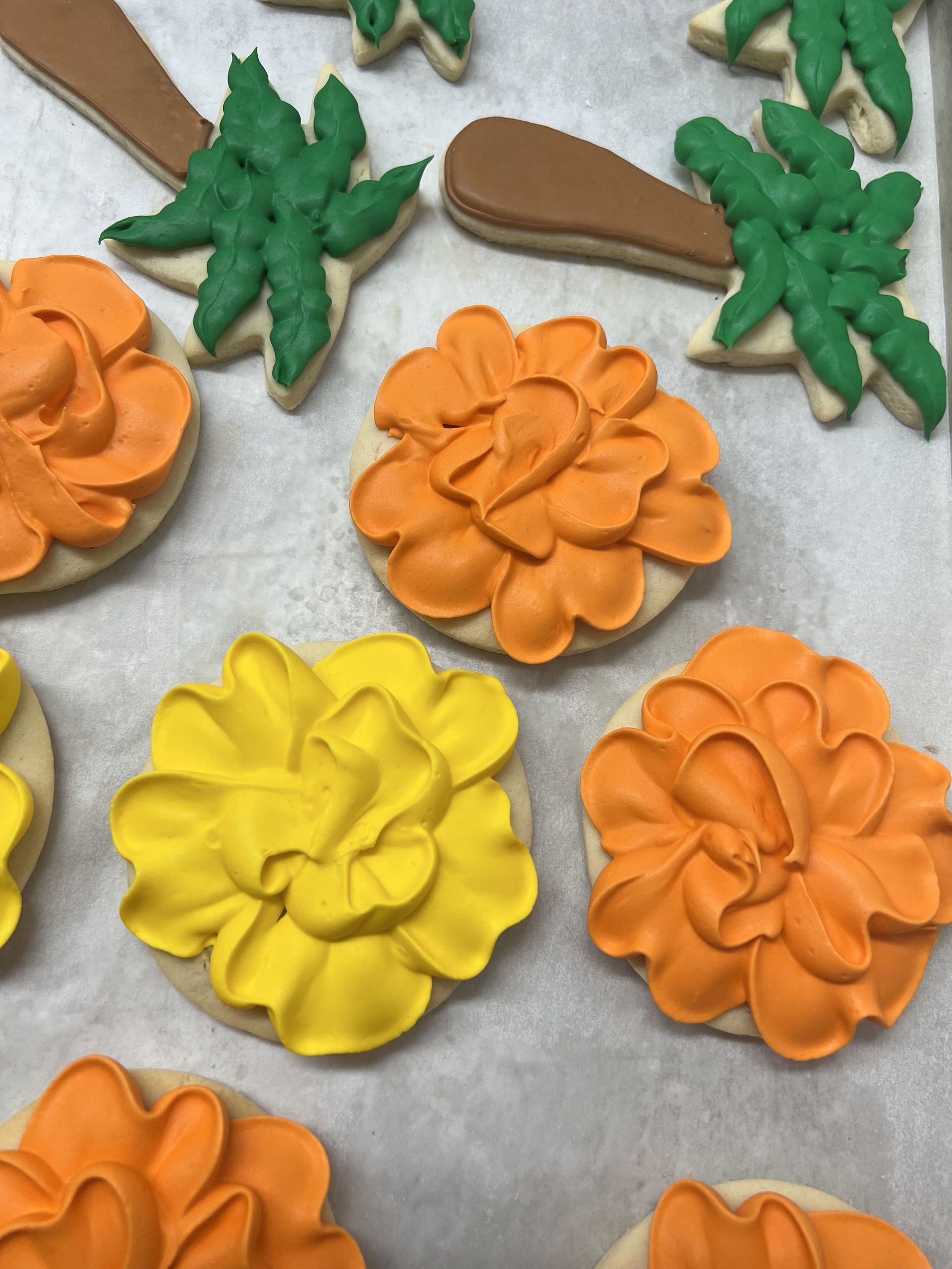 a bunch of cookies decorated with yellow and orange flowers and green leaves