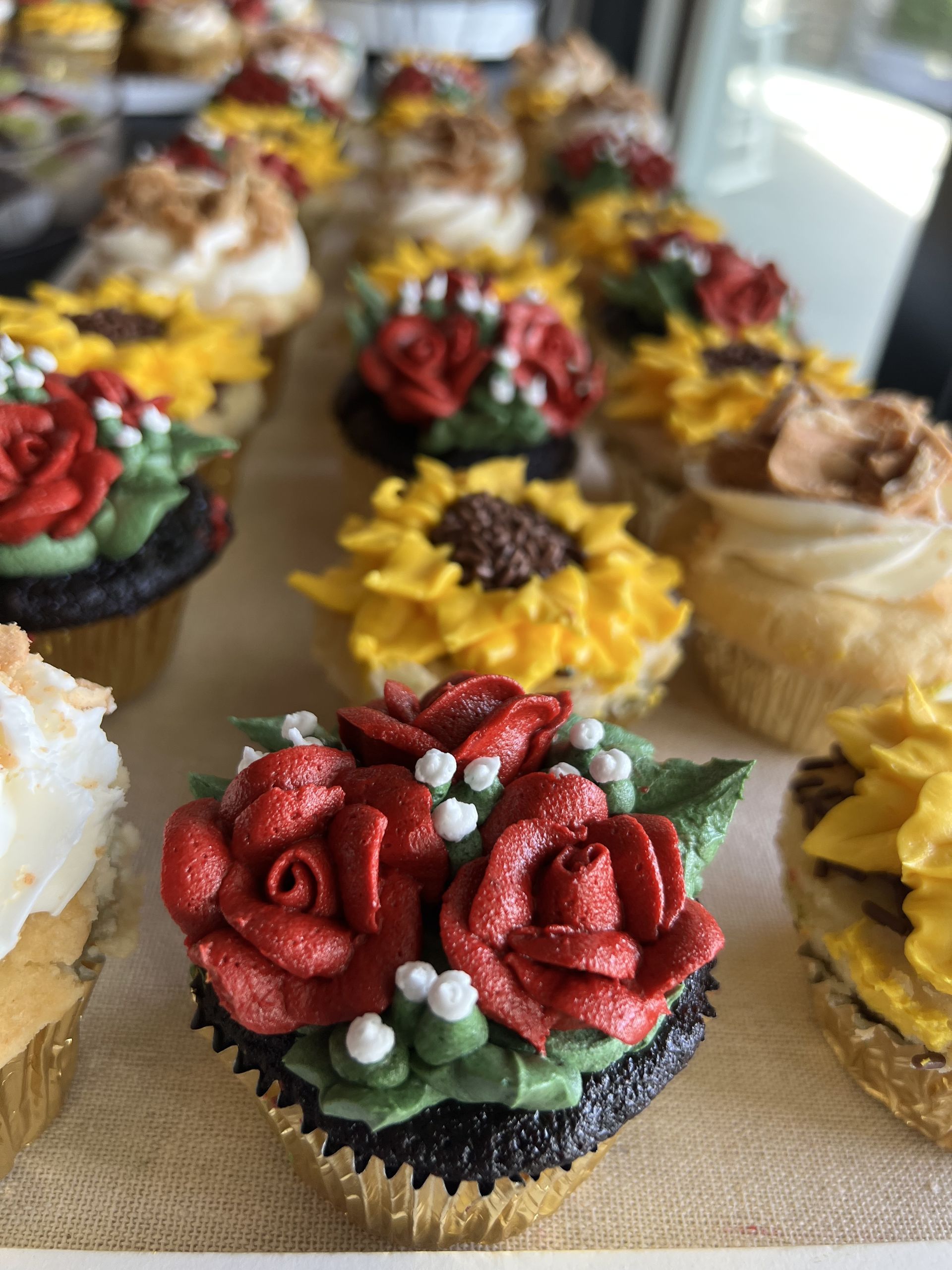 a bunch of cupcakes with flowers on them are sitting on a table .