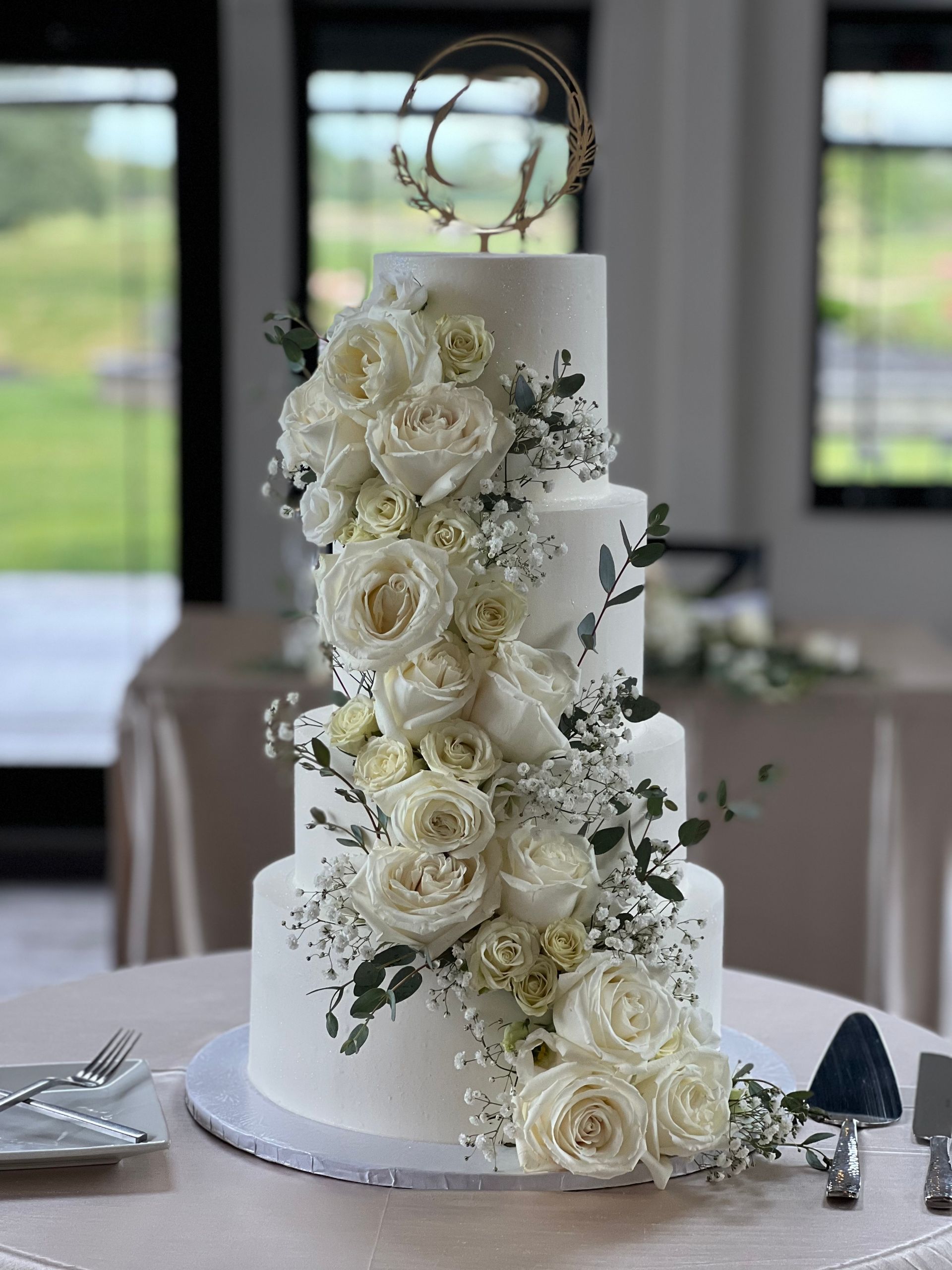 a white wedding cake with white roses and baby 's breath on a table .