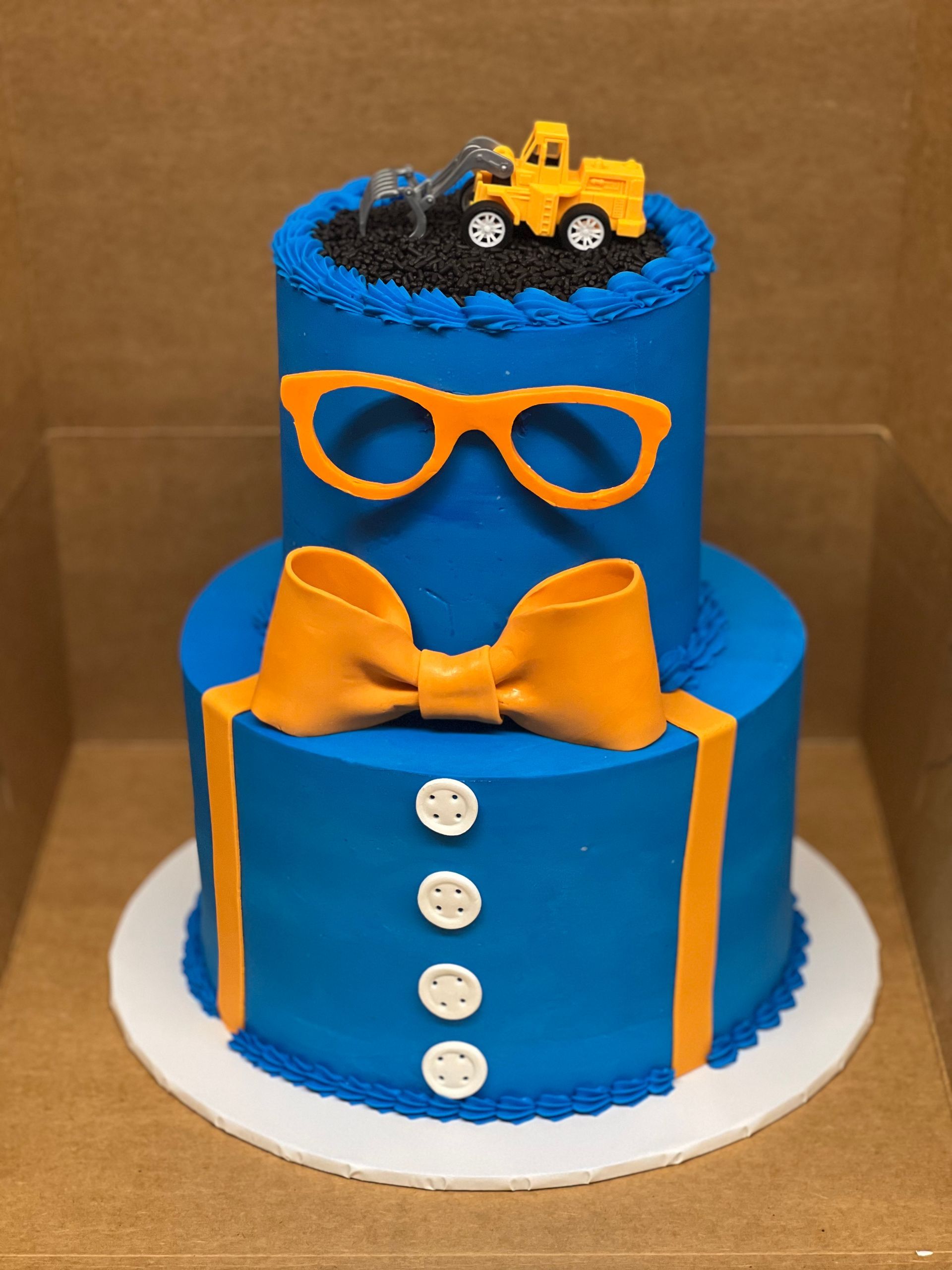 a blue and orange cake with a bow tie and glasses on top .