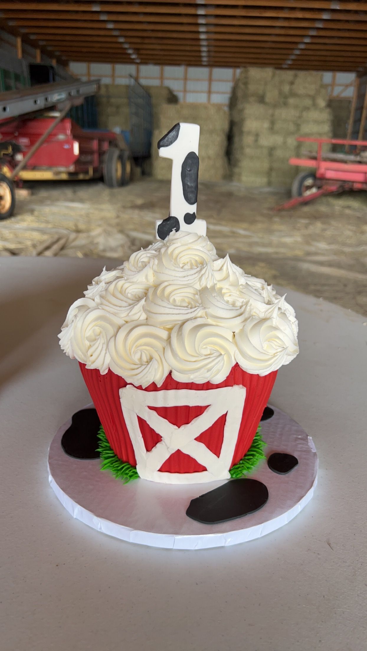 a cupcake with a barn and a cow on it is sitting on a table .